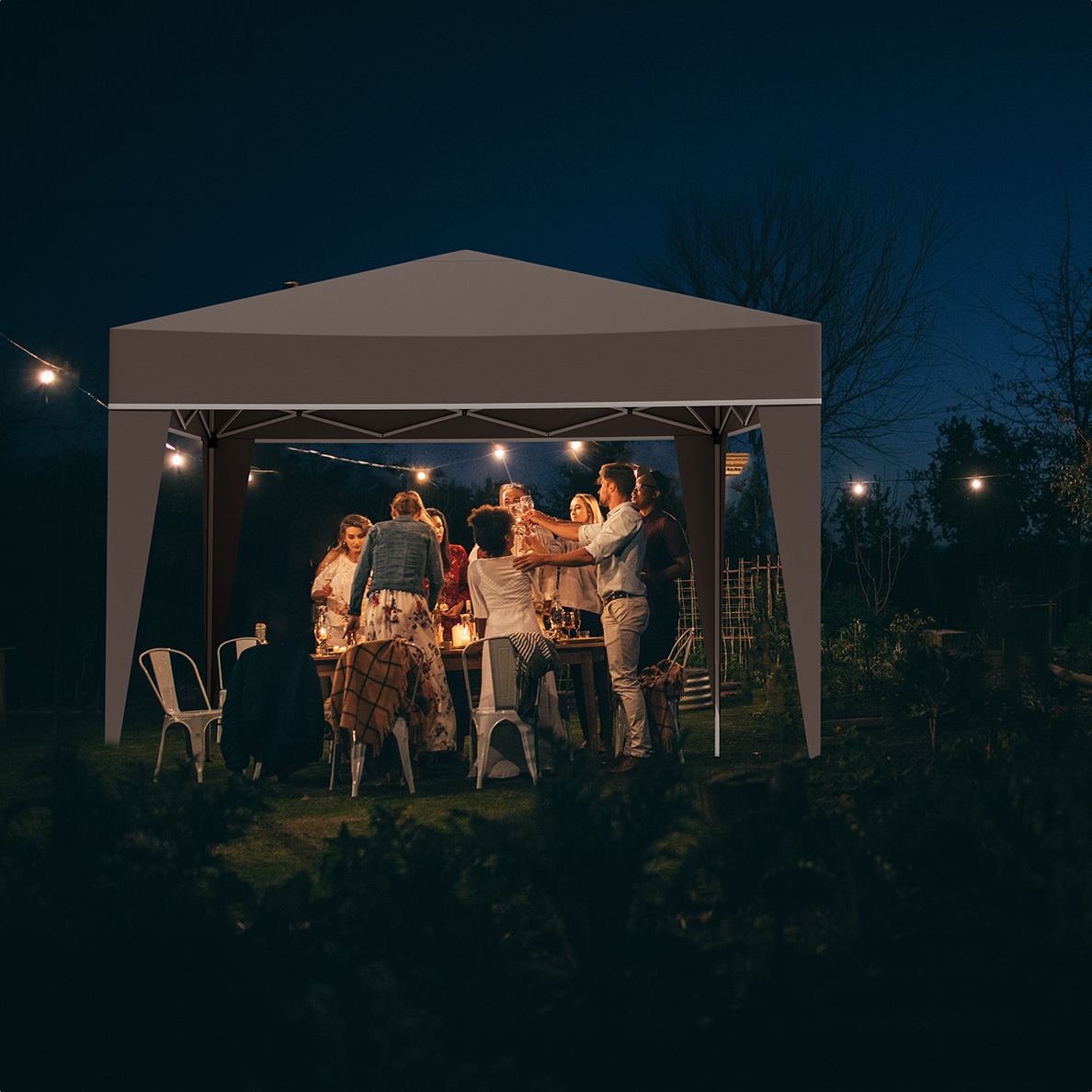 Des gens célèbrent sous un gazebo brun la nuit, éclairé par des guirlandes lumineuses.