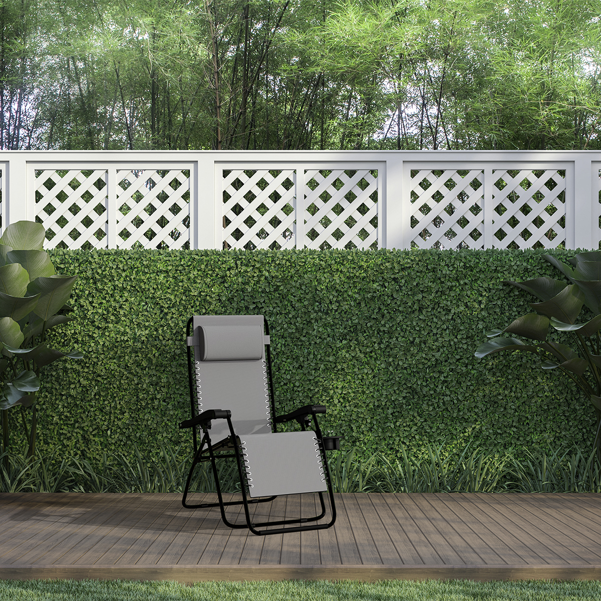Een grijze loungestoel staat op een houten terras voor een groene heg.