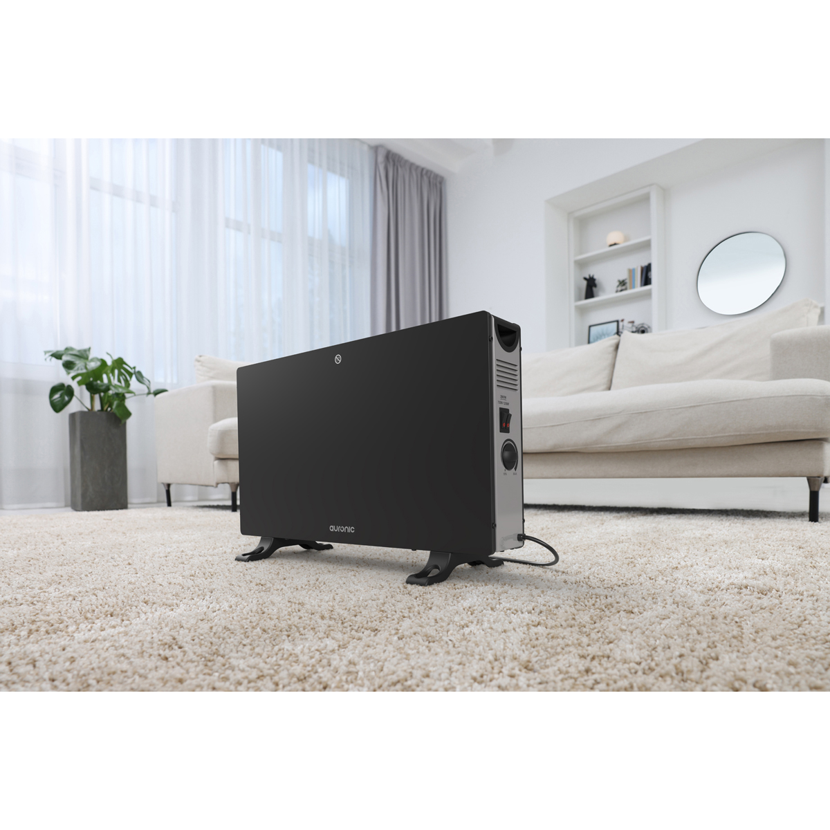 A black heater sits on a cream carpet in front of a sofa.
