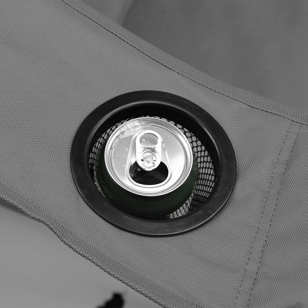 Een frisdrankblikje in een grijze stoffen bekerhouder op een stoel.
