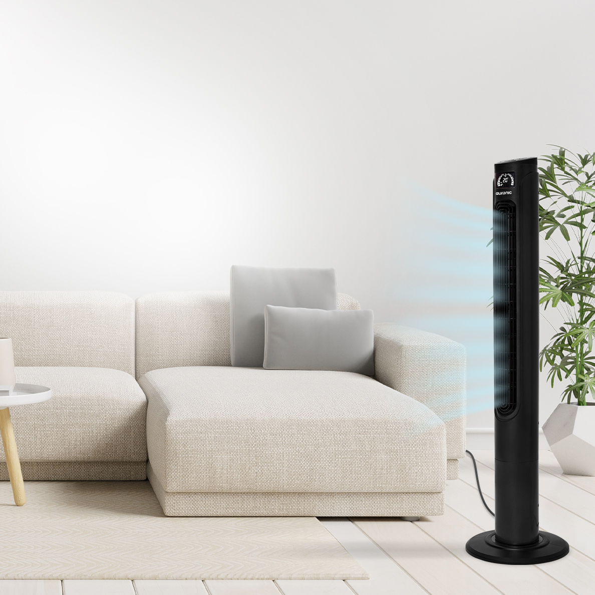 Un ventilateur tour noir fonctionne dans un salon lumineux à côté d'un canapé.