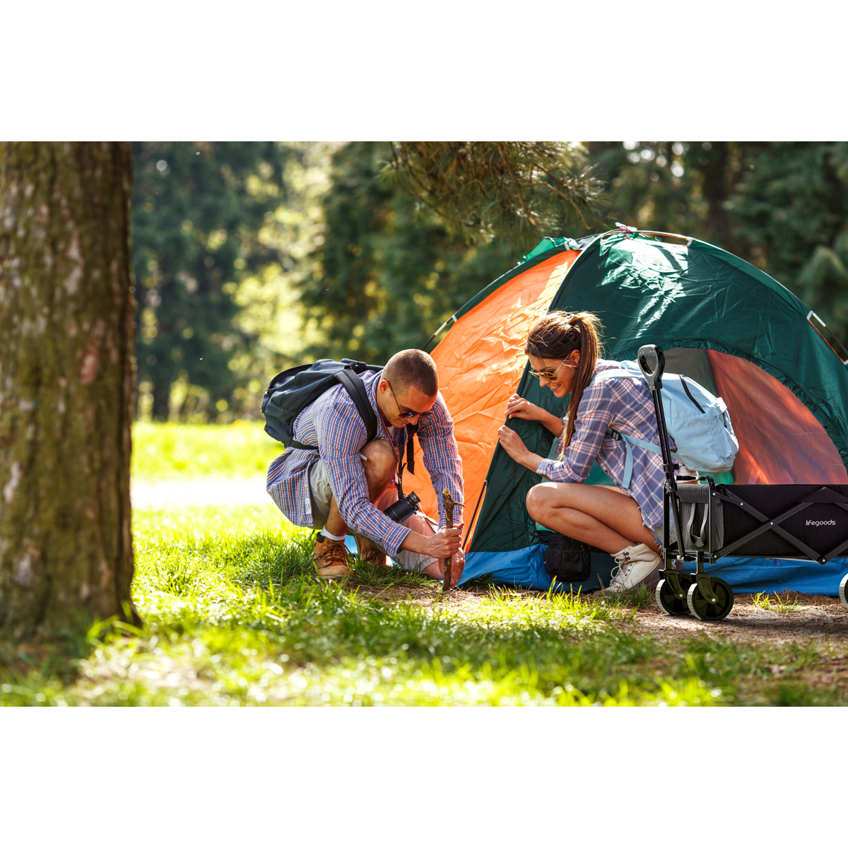 A man and a woman are setting up a tent in a forest.