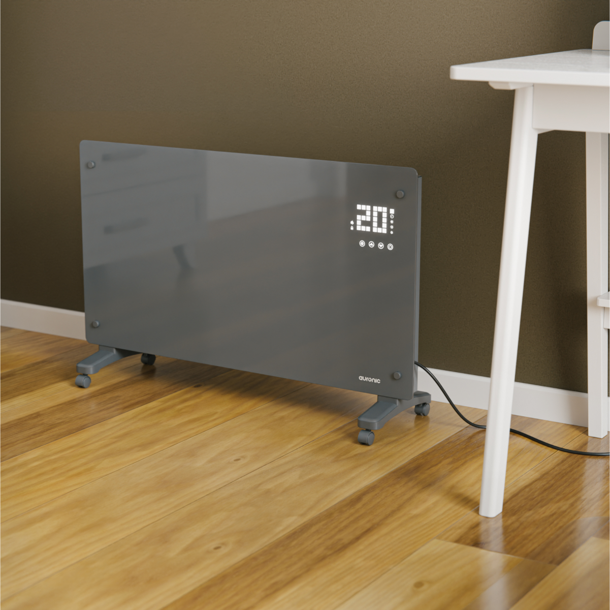 A grey electric heater with wheels and digital display sits on a wooden floor next to a white table.