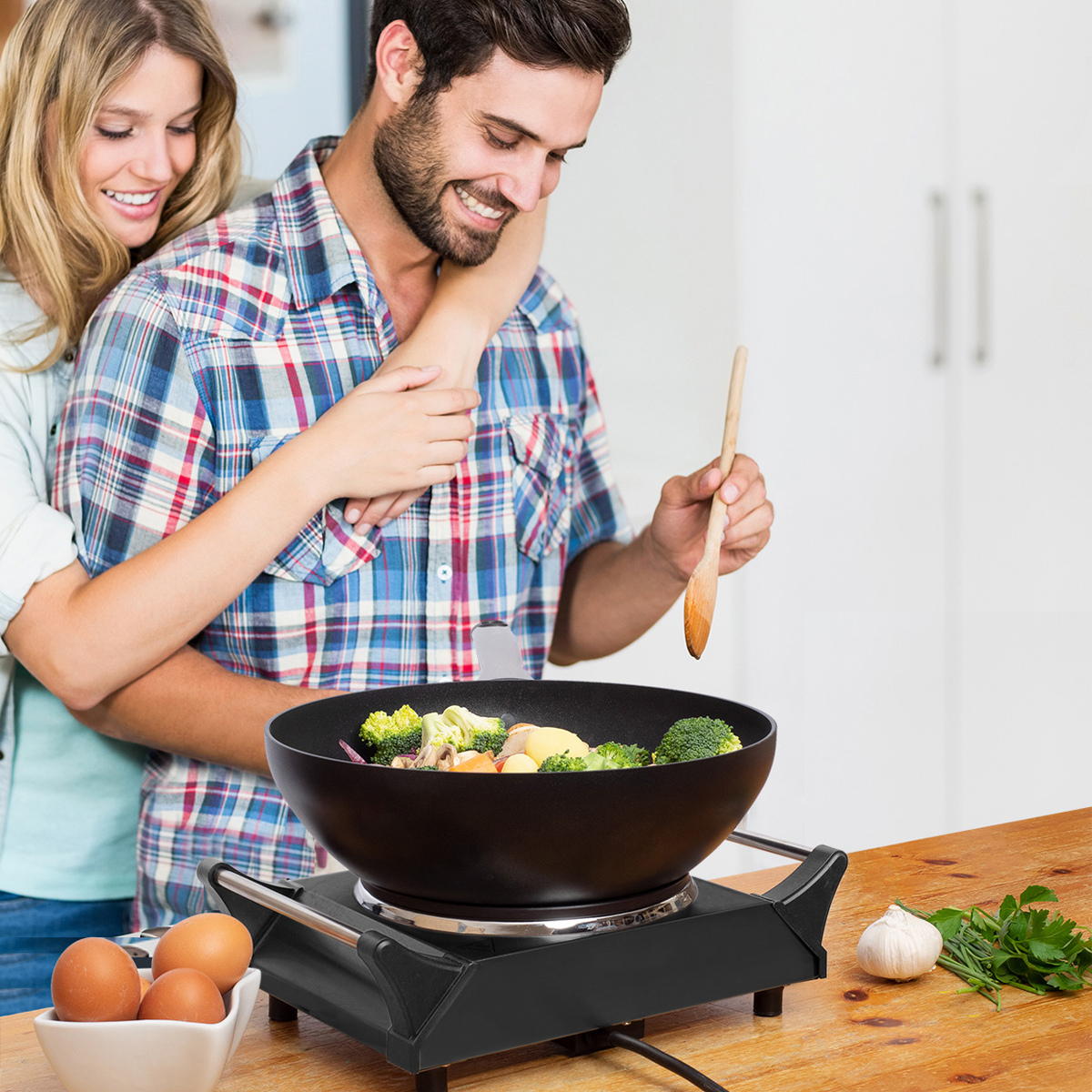 Couple cuisinant un sauté dans un wok avec brocoli et pommes de terre. Ail, œufs et persil à proximité.