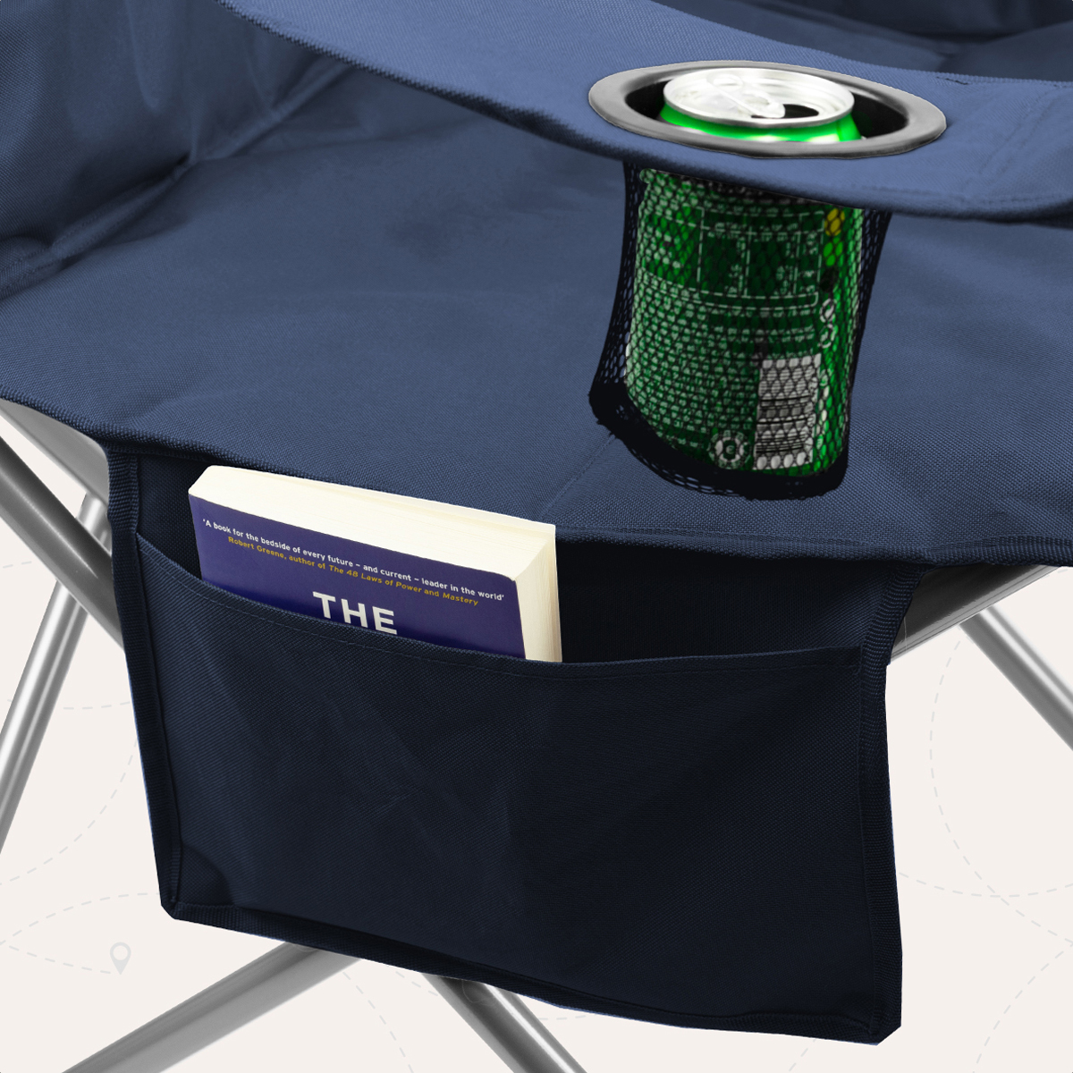 A book and a can in a navy fabric pocket of a camping chair.