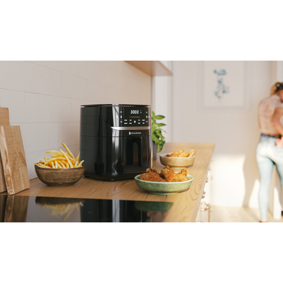 A black air fryer with french fries and chicken wings on a wooden counter.