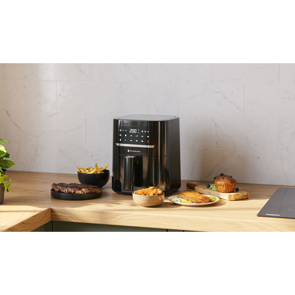 Black air fryer with steaks, fries, fish, and muffins on a wooden counter.