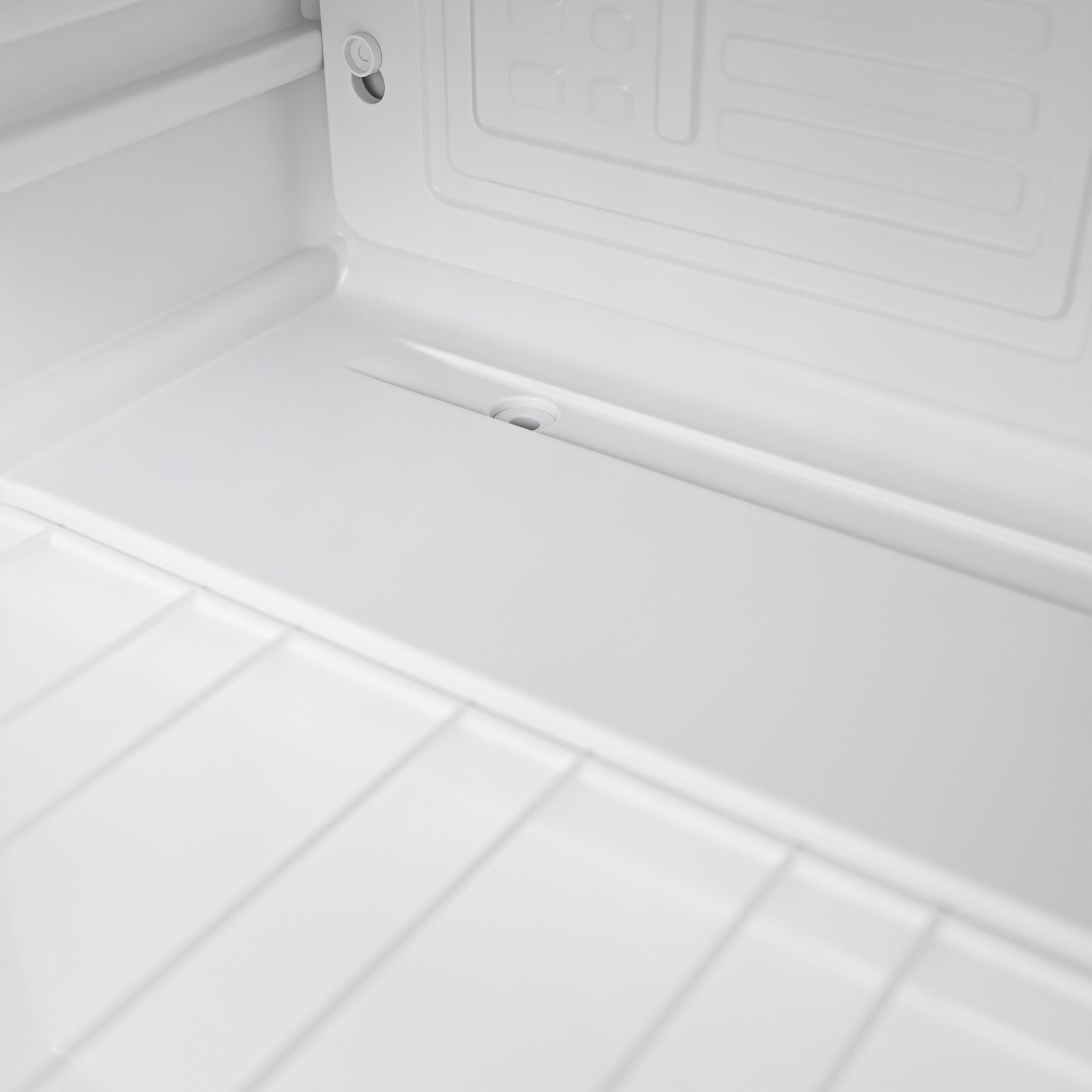 Interieur van een witte koelkast met lattenbodem en afvoerputje.