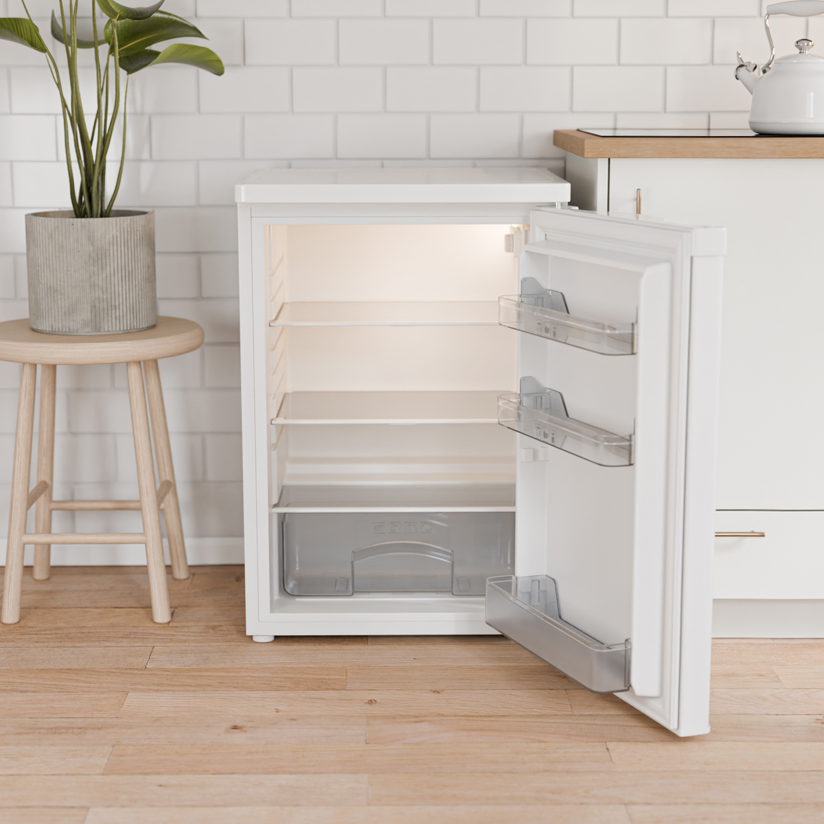 Un réfrigérateur blanc ouvert et vide avec des étagères en verre et un tiroir.