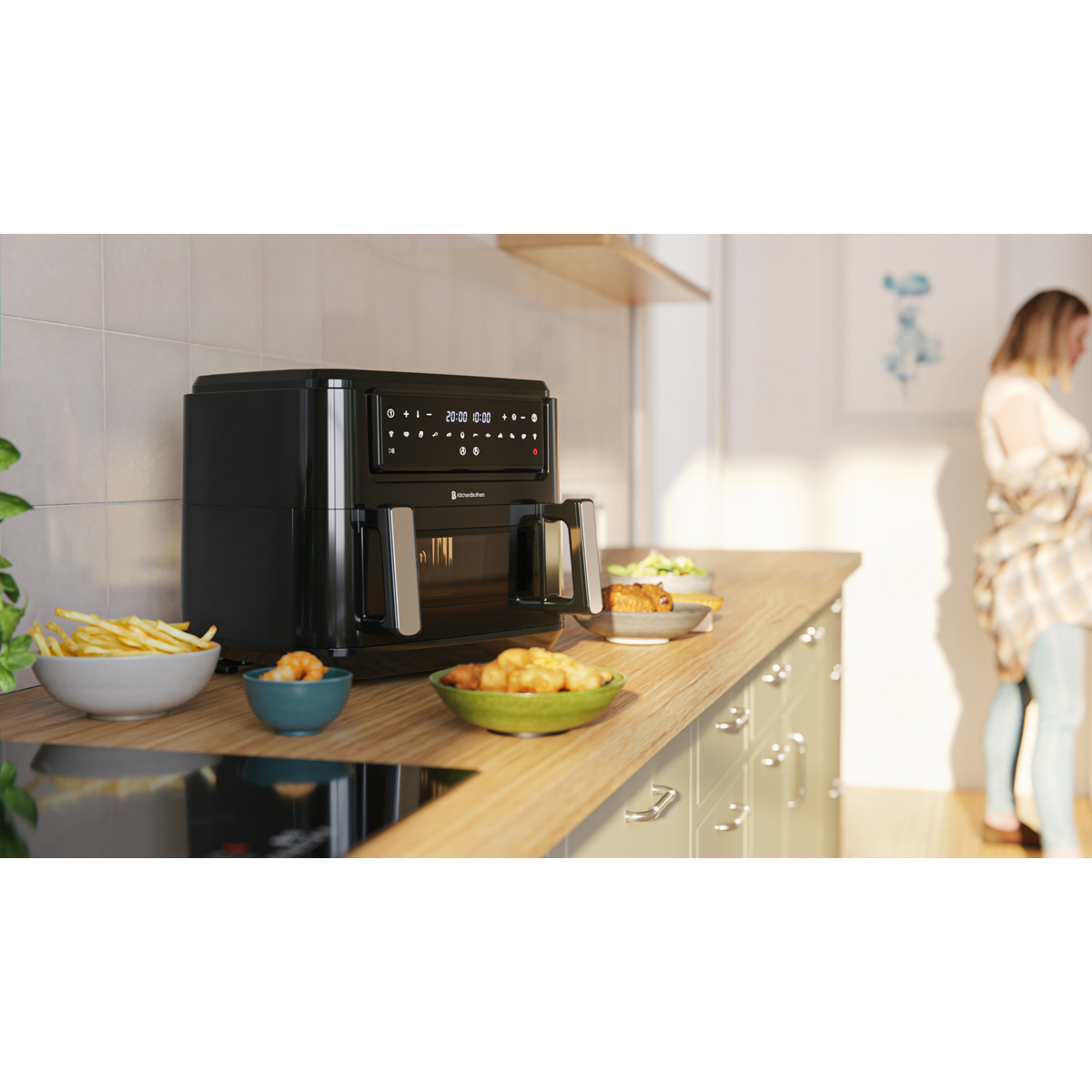 A black air fryer with french fries, shrimp, and snacks beside it.