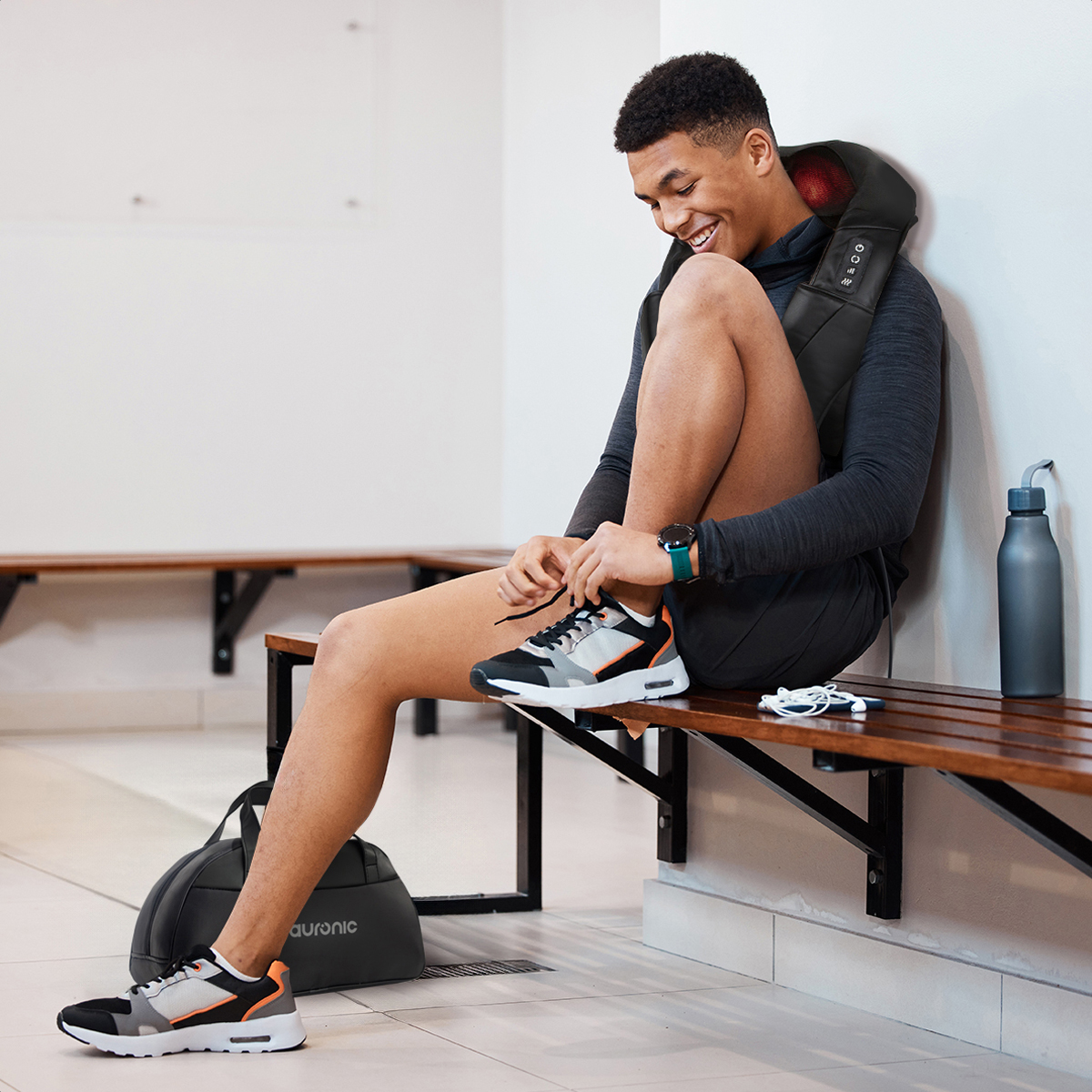 A man wearing a neck massager ties his shoelaces on a wooden bench.