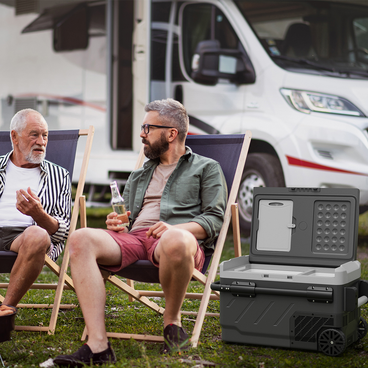 Twee mannen zitten buiten in stoelen bij een camper, met een draagbare koelbox ervoor.