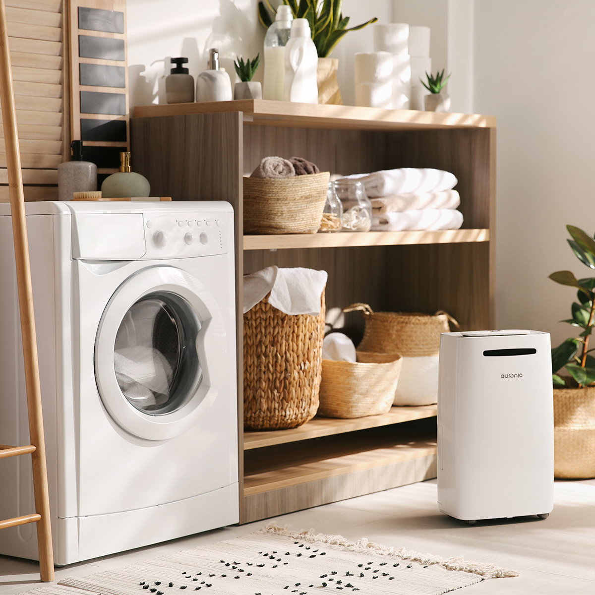 Een witte wasmachine, planken met handdoeken, manden en een witte luchtontvochtiger.