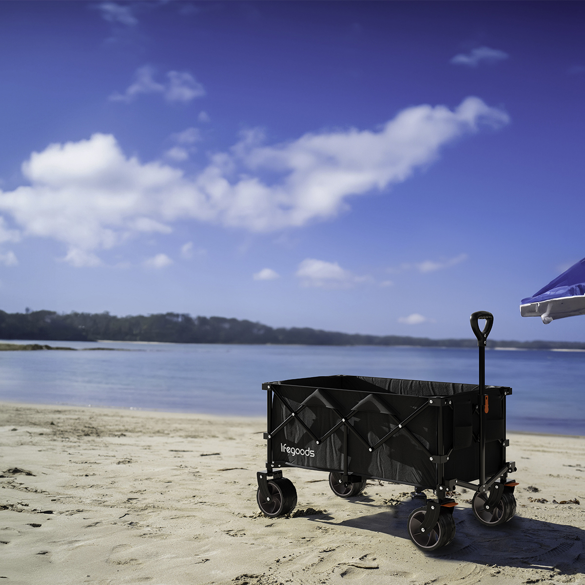 A black beach wagon sits on the sandy shore beside the ocean.