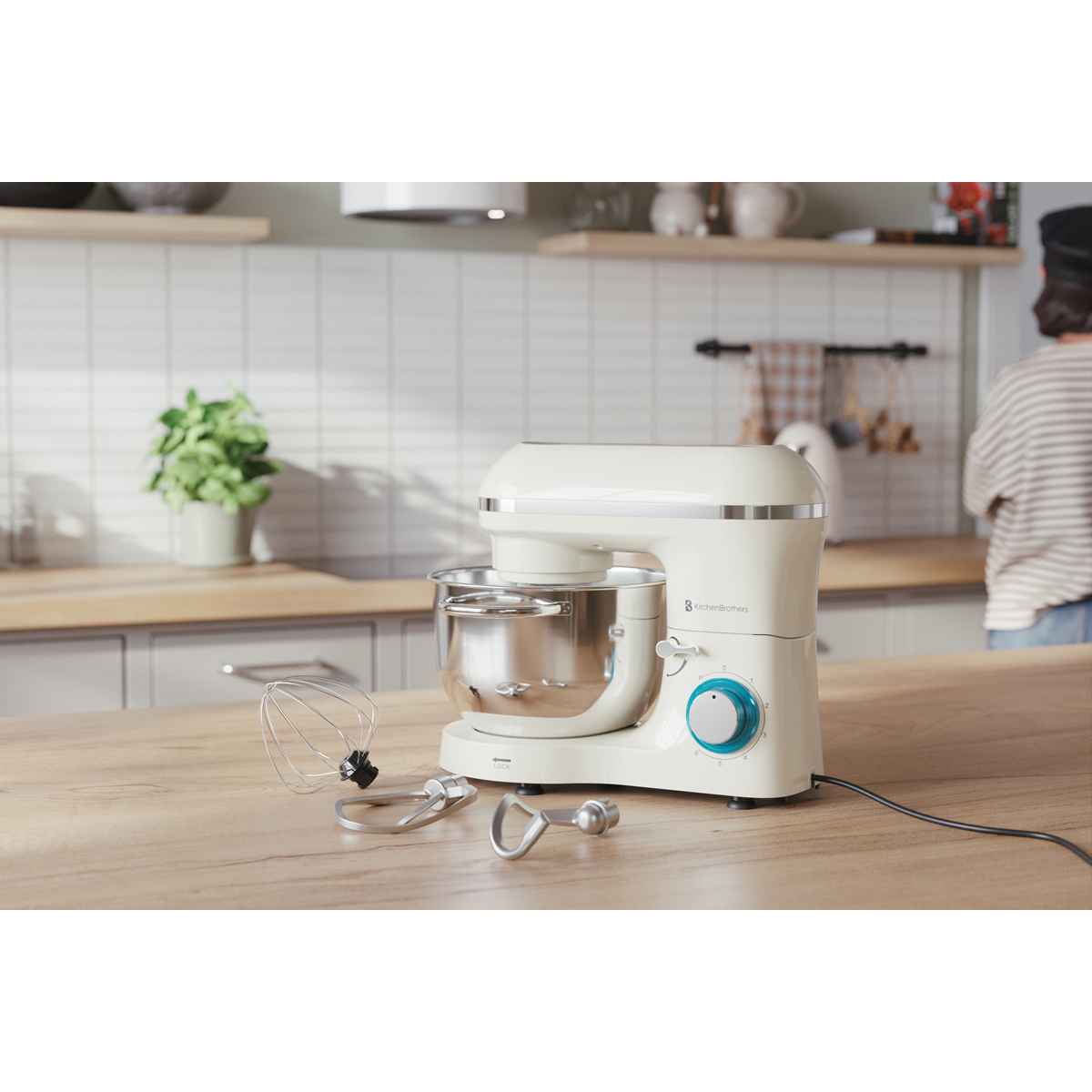 Een crème-kleurige standmixer op een houten aanrecht naast garde-accessoires.