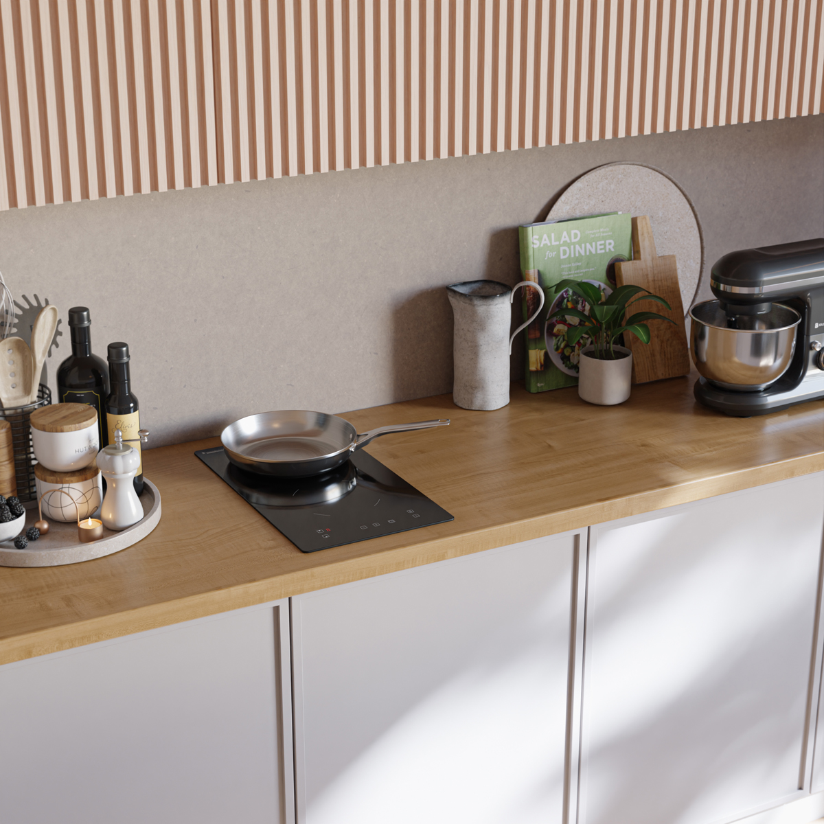 A kitchen countertop with a cooktop, frying pan, spice grinder, bottles, and a mixer.