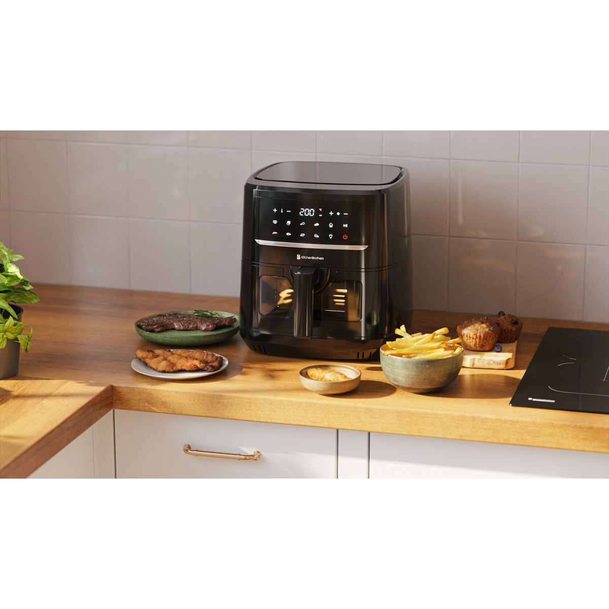 Black air fryer with food like fries, meat, and muffins next to it.