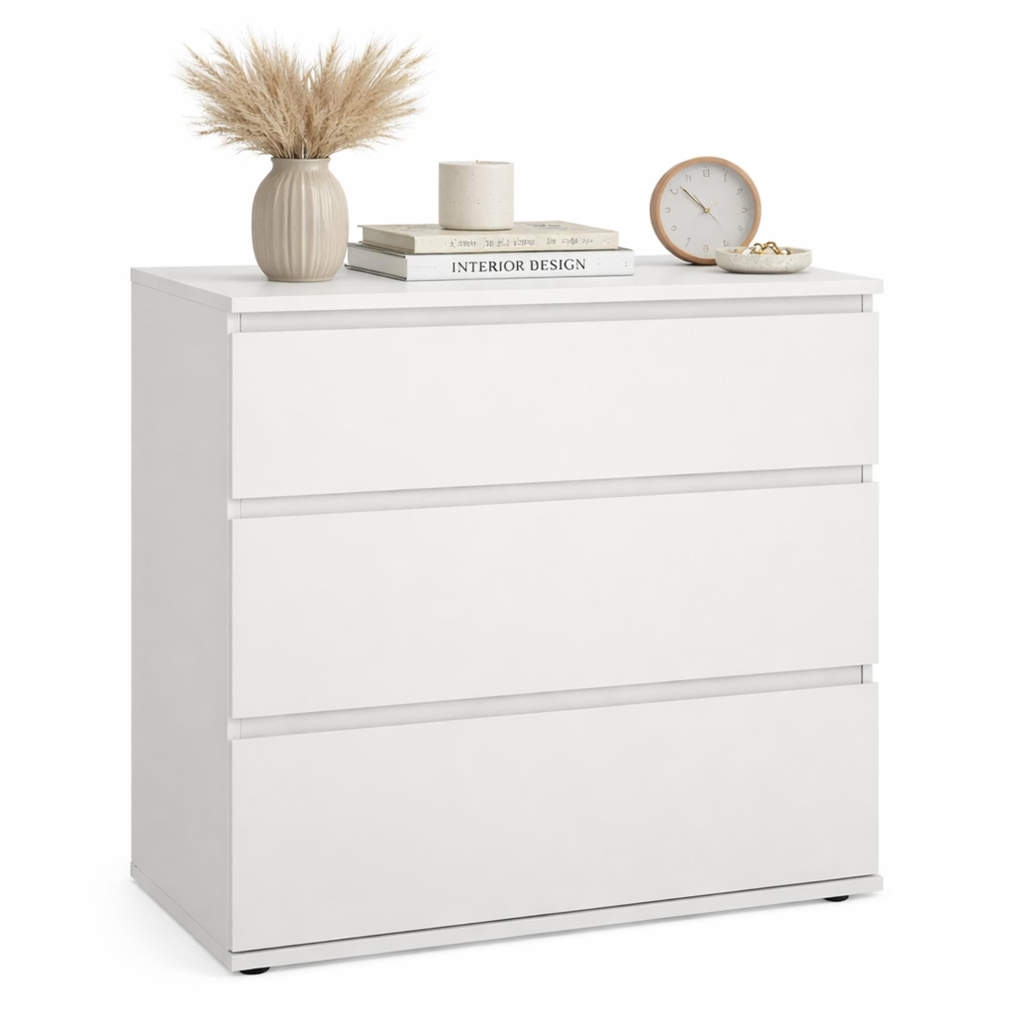Cómoda blanca de tres cajones decorada con jarrón, vela y reloj.
