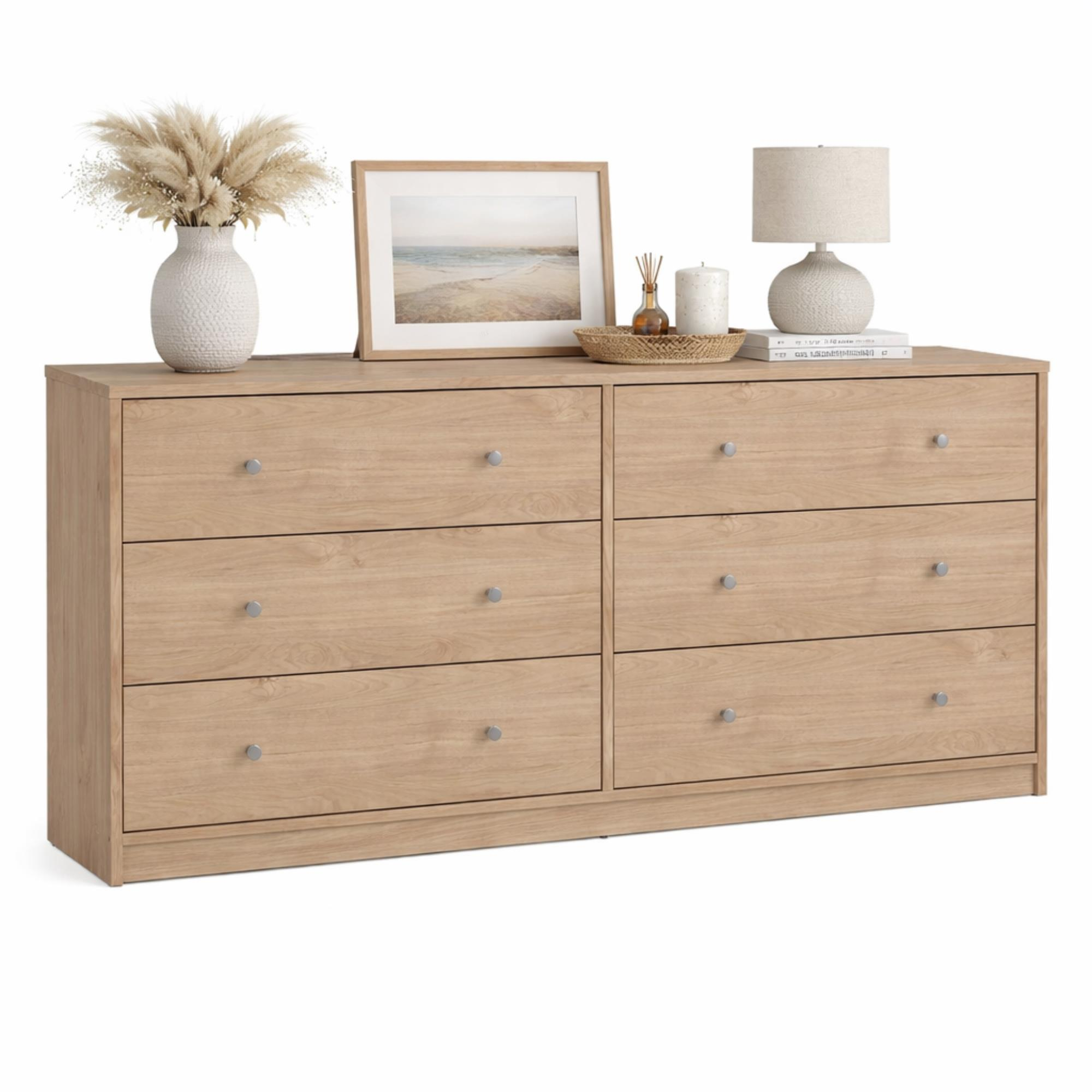 Cómoda de madera con seis cajones, decorada con jarrón, cuadro y lámpara.