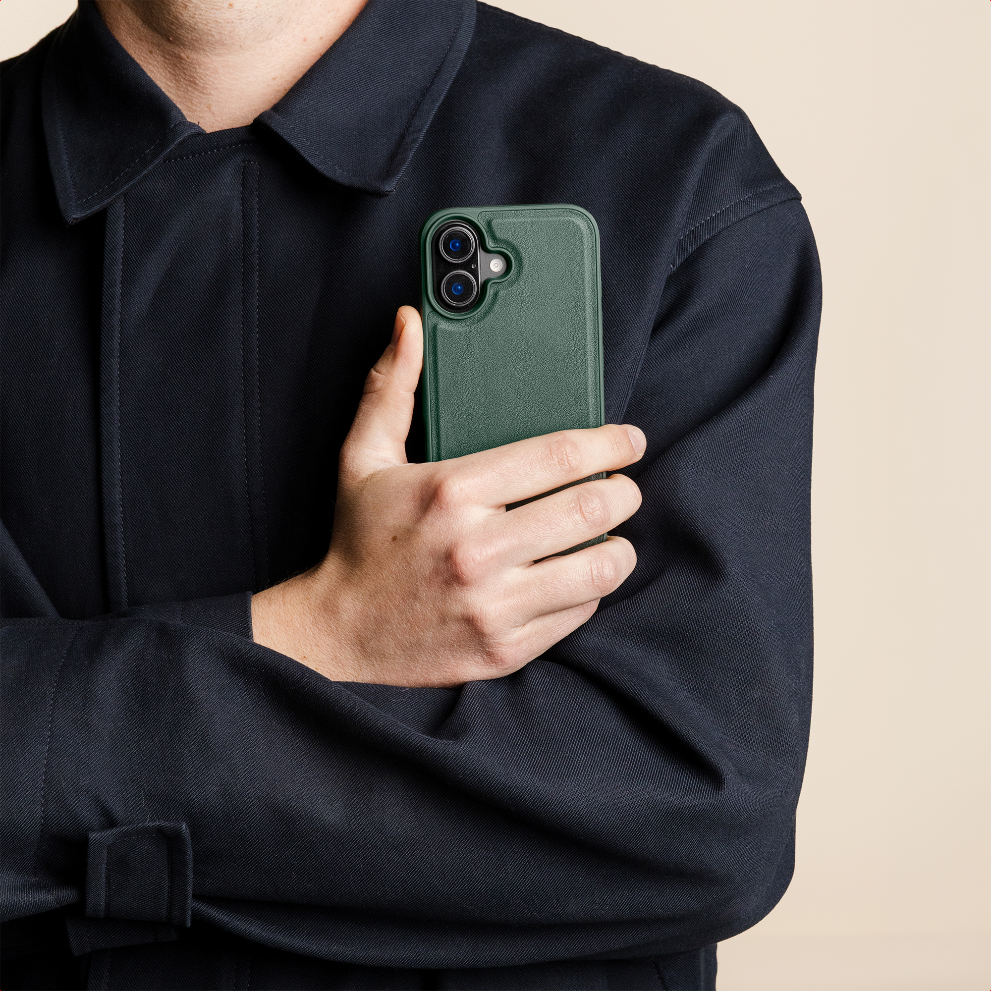 Een hand houdt een donkergroene iPhone met twee camera's vast.