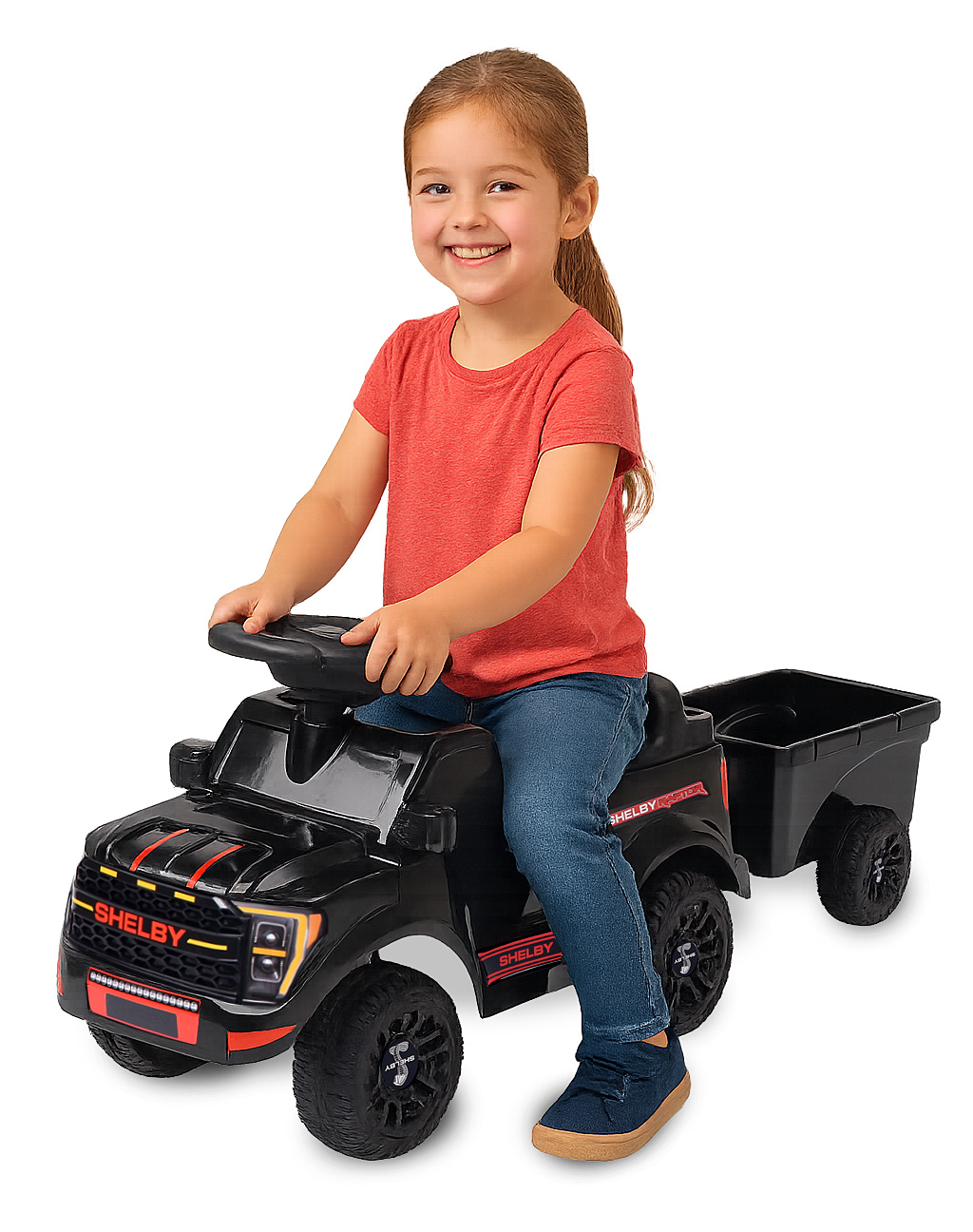 Ein kleines Mädchen fährt einen schwarzen Spielzeug-Pick-up mit Anhänger.