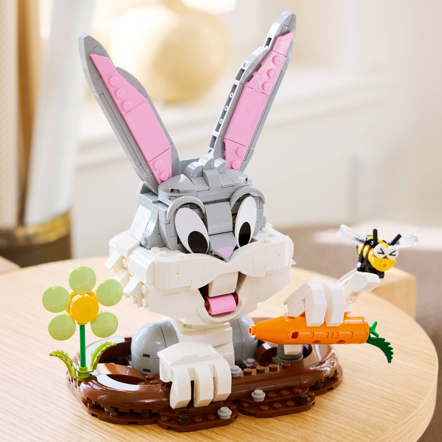 Ahşap bir masada havuç tutan Lego Bugs Bunny modeli ve arı.