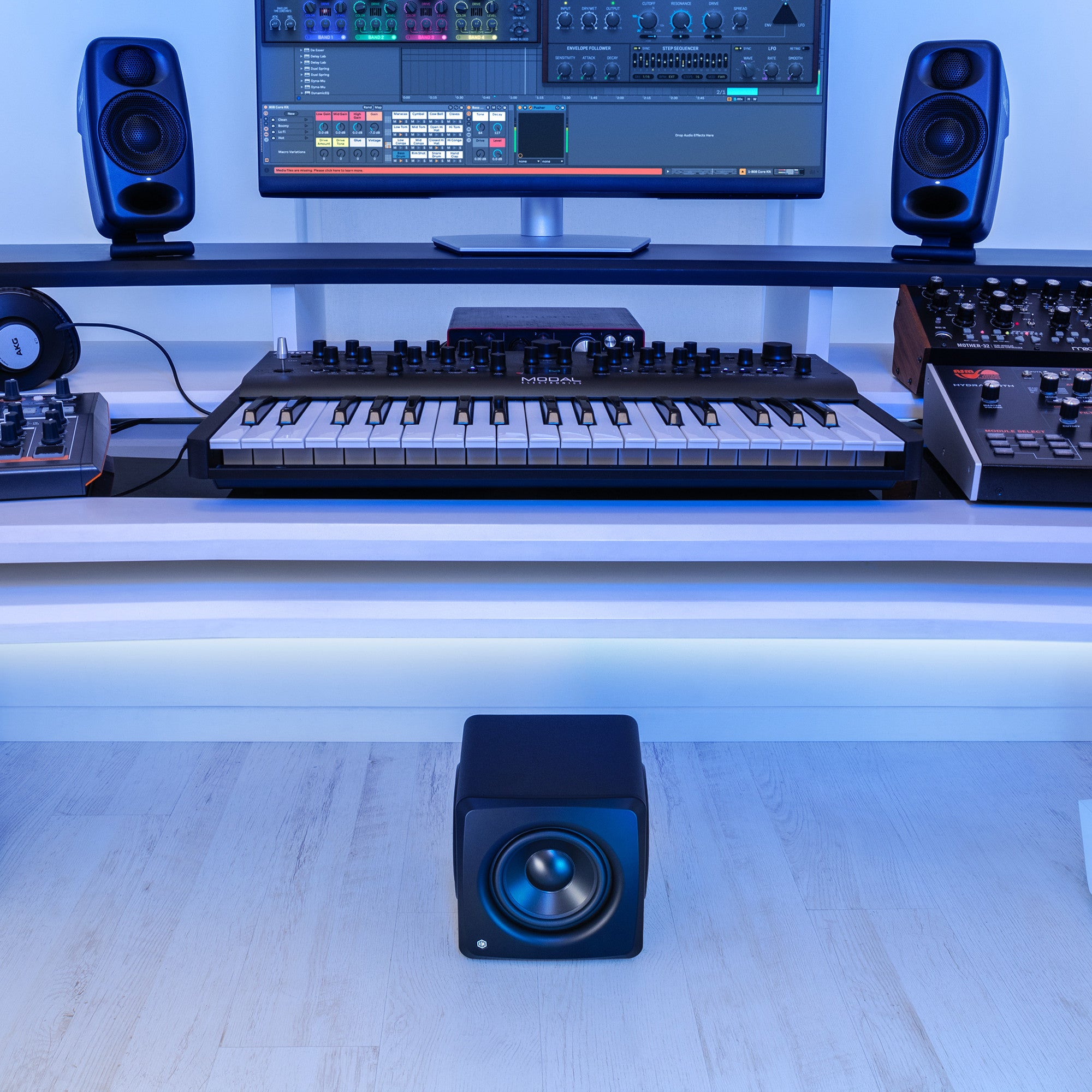 Un setup da studio con monitor, sintetizzatori, cuffie e altoparlanti.