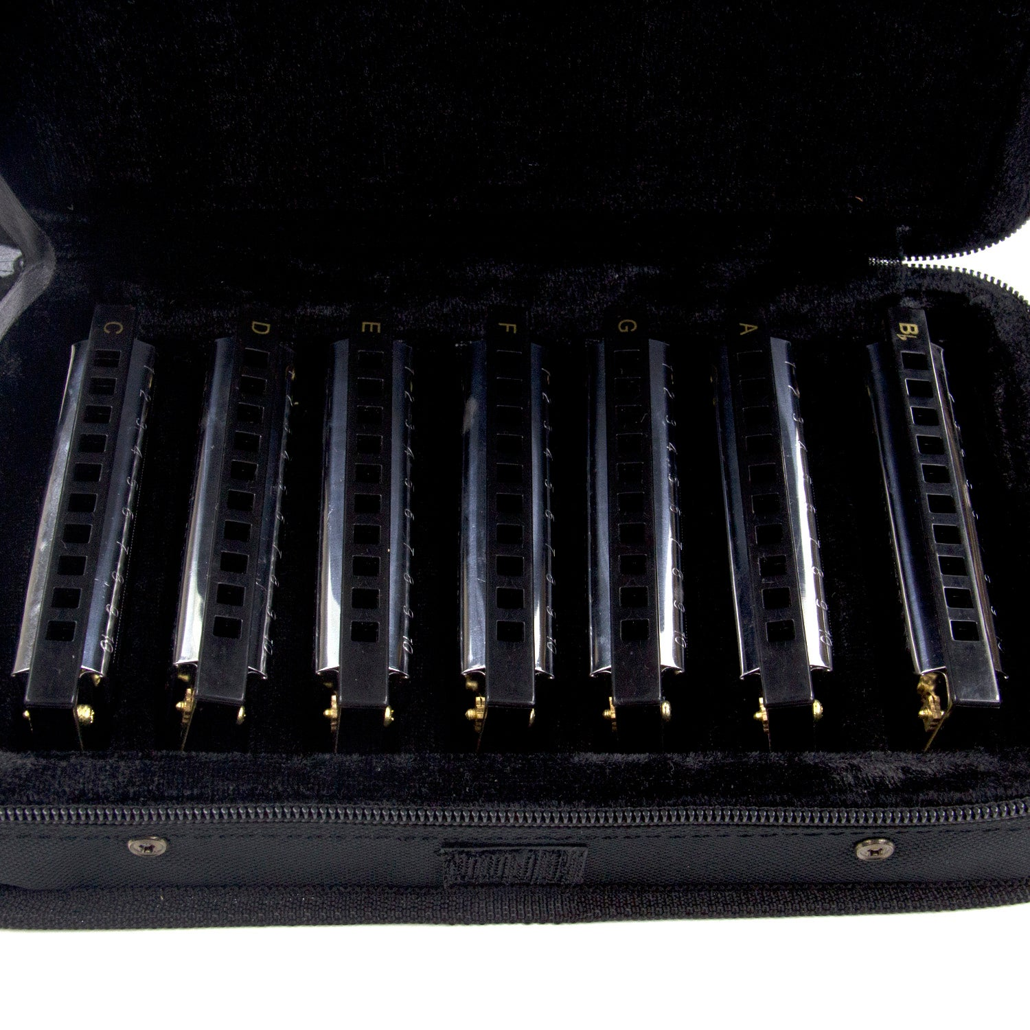 A black velvet case holding nine harmonicas labeled with notes.