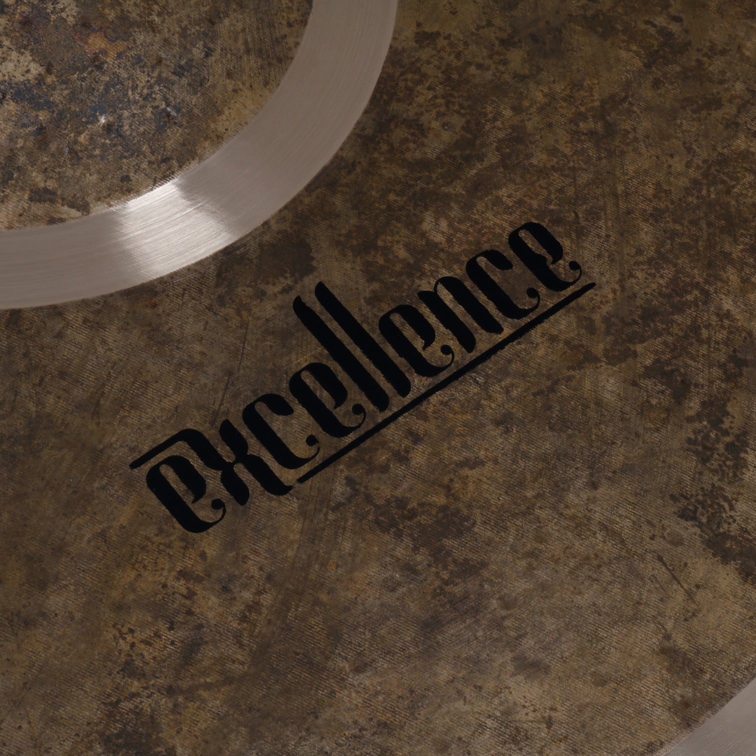 Close-up of a bronze cymbal with the word "Excellence" in black font.