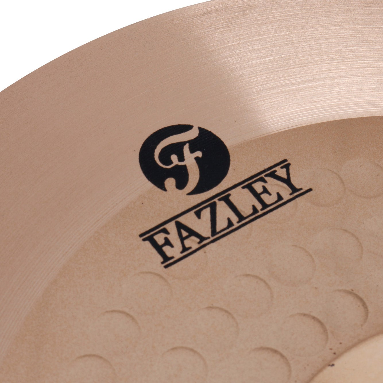 A close-up of a bronze cymbal with the Fazley logo. It has concentric circles.