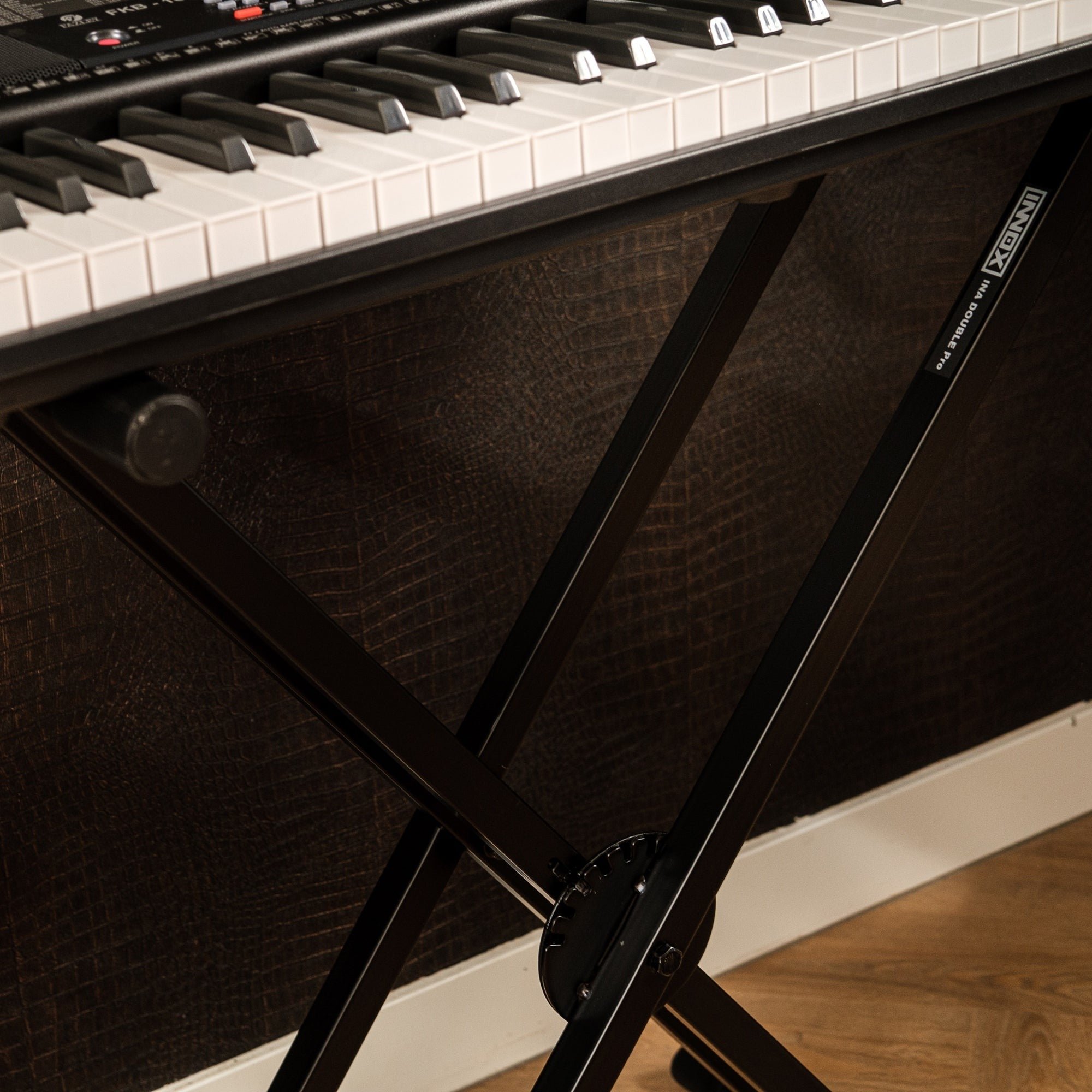 A black keyboard stand supports a keyboard with white and black keys.