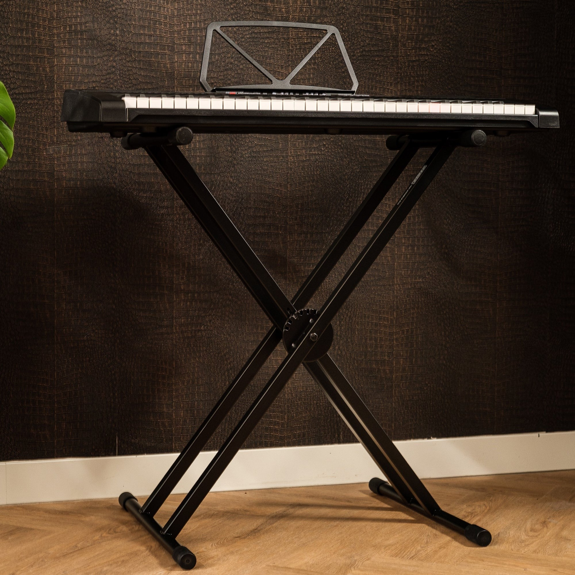 A black keyboard rests on an X-shaped stand against brown crocodile-textured wallpaper.