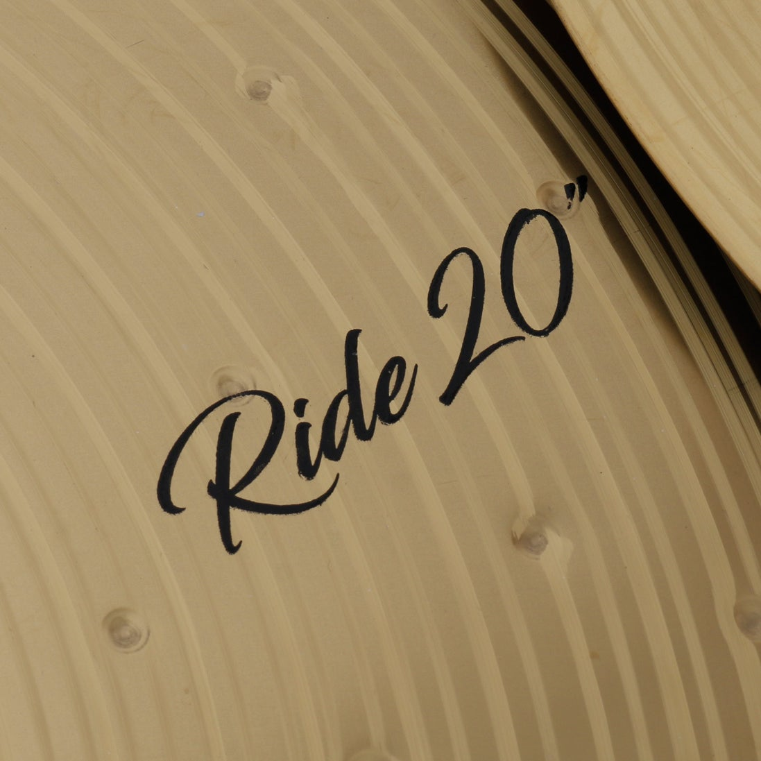 Close-up of a golden cymbal with "Ride 20" text on it.