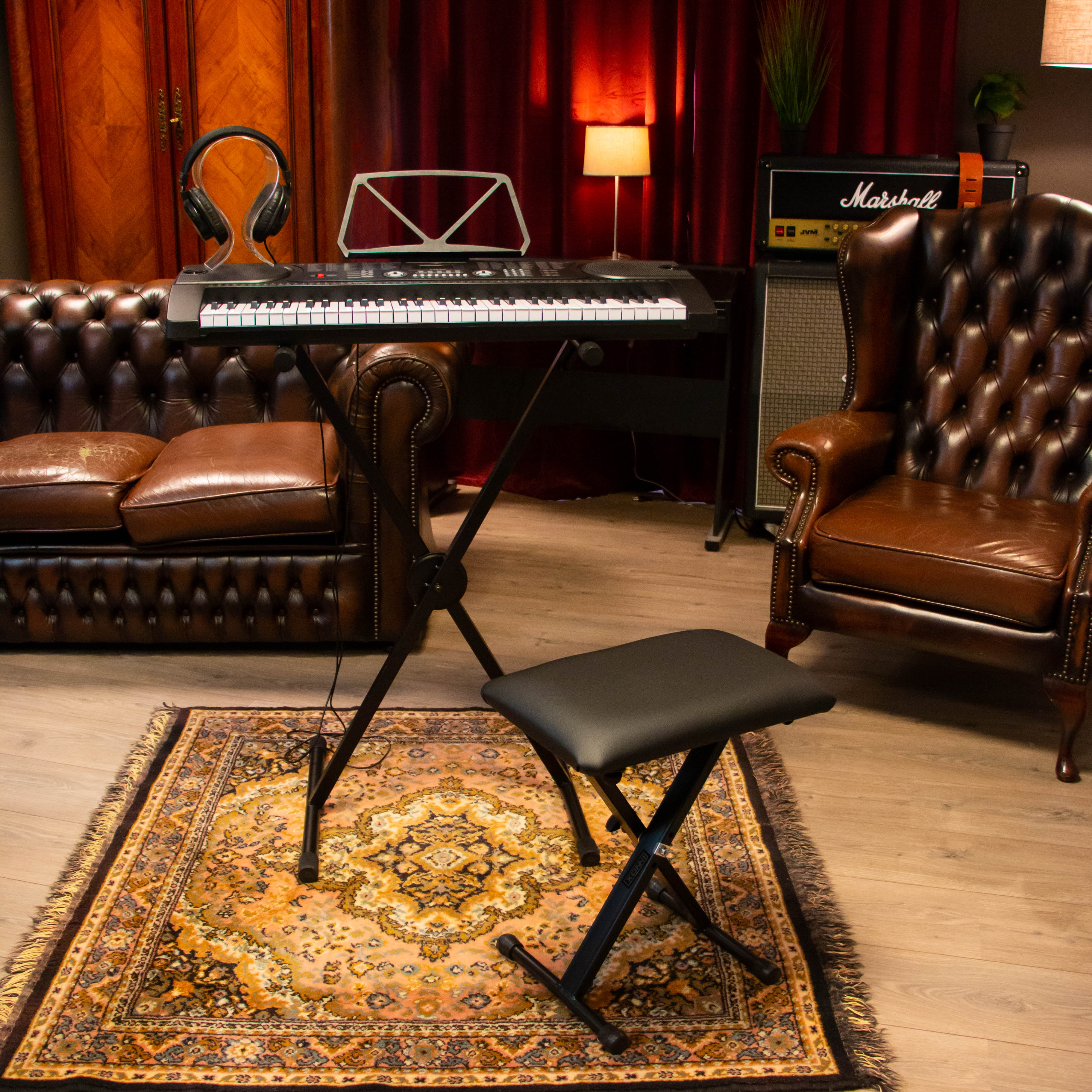 Een muziekkamer met leren bank, keyboard, Marshall versterker en patroonkleed.