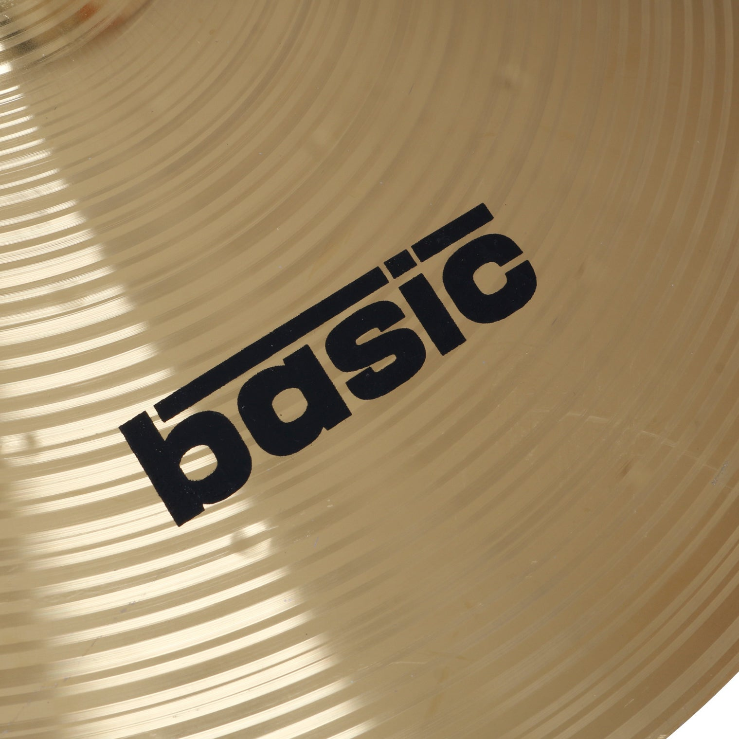 A gold cymbal with the word basic in black letters. Concentric circles on surface.