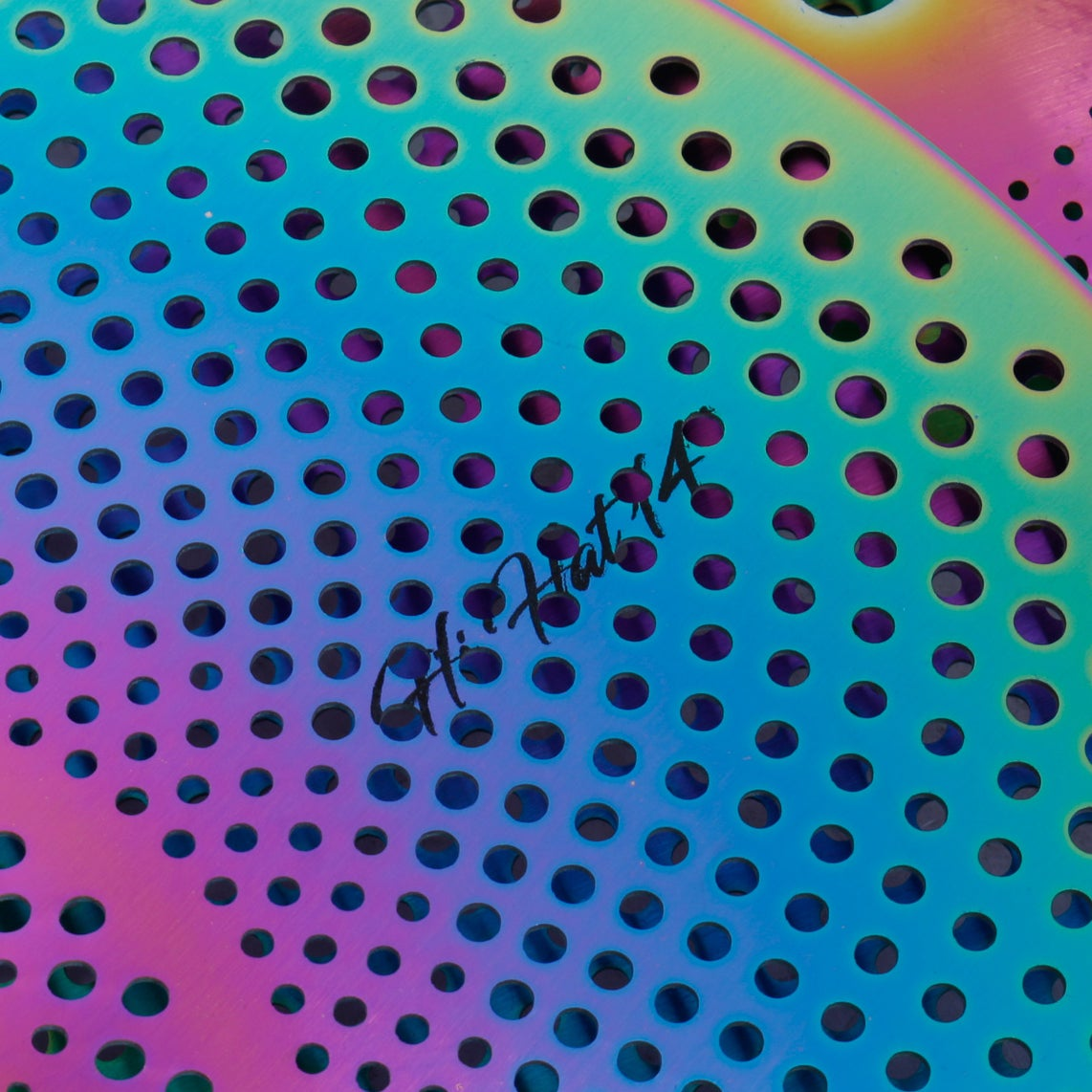 A metallic object with a hole pattern in blue, purple, and green hues. Text: Hi Hat 14.