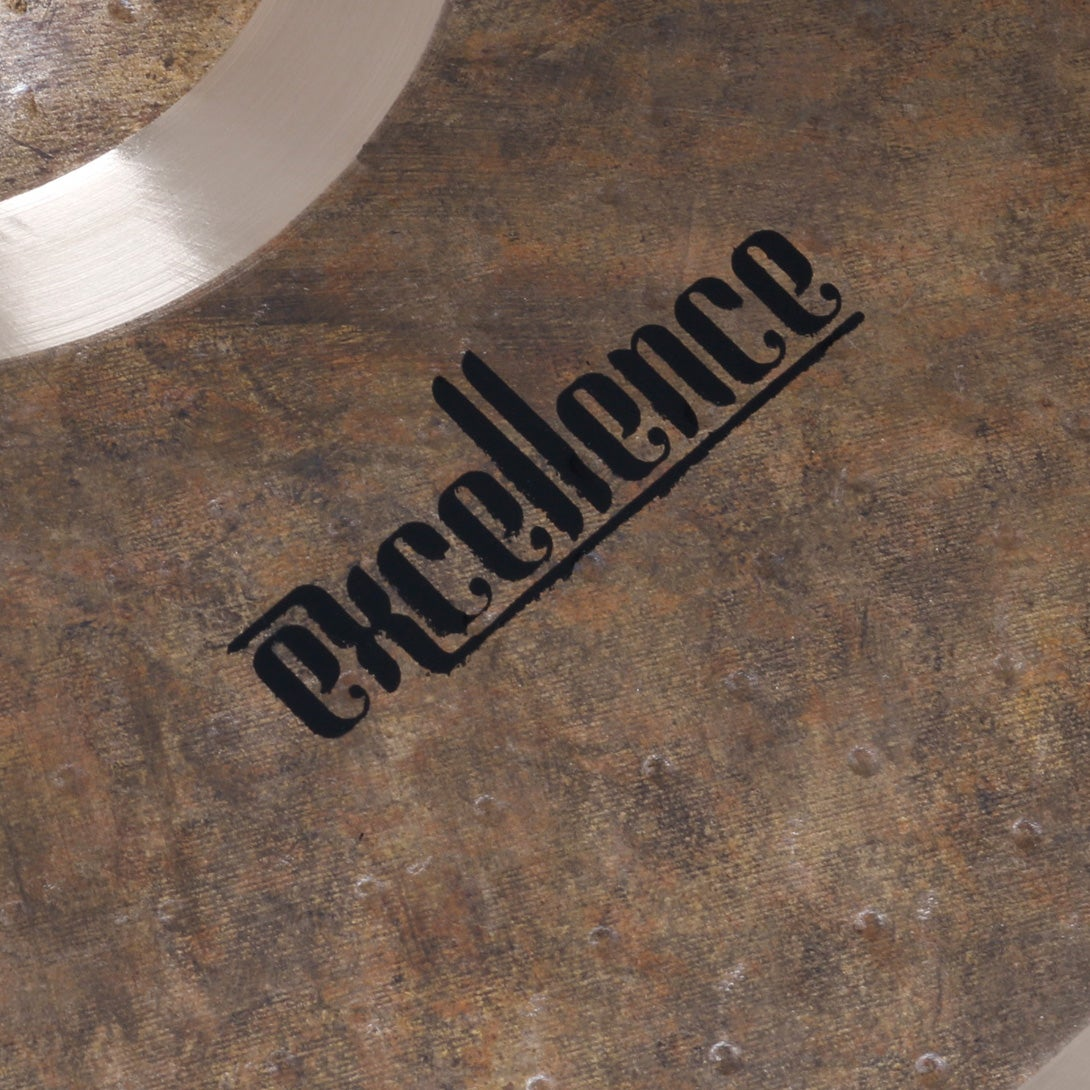 The word "Excellence" is written in black on a rustic, metallic cymbal.