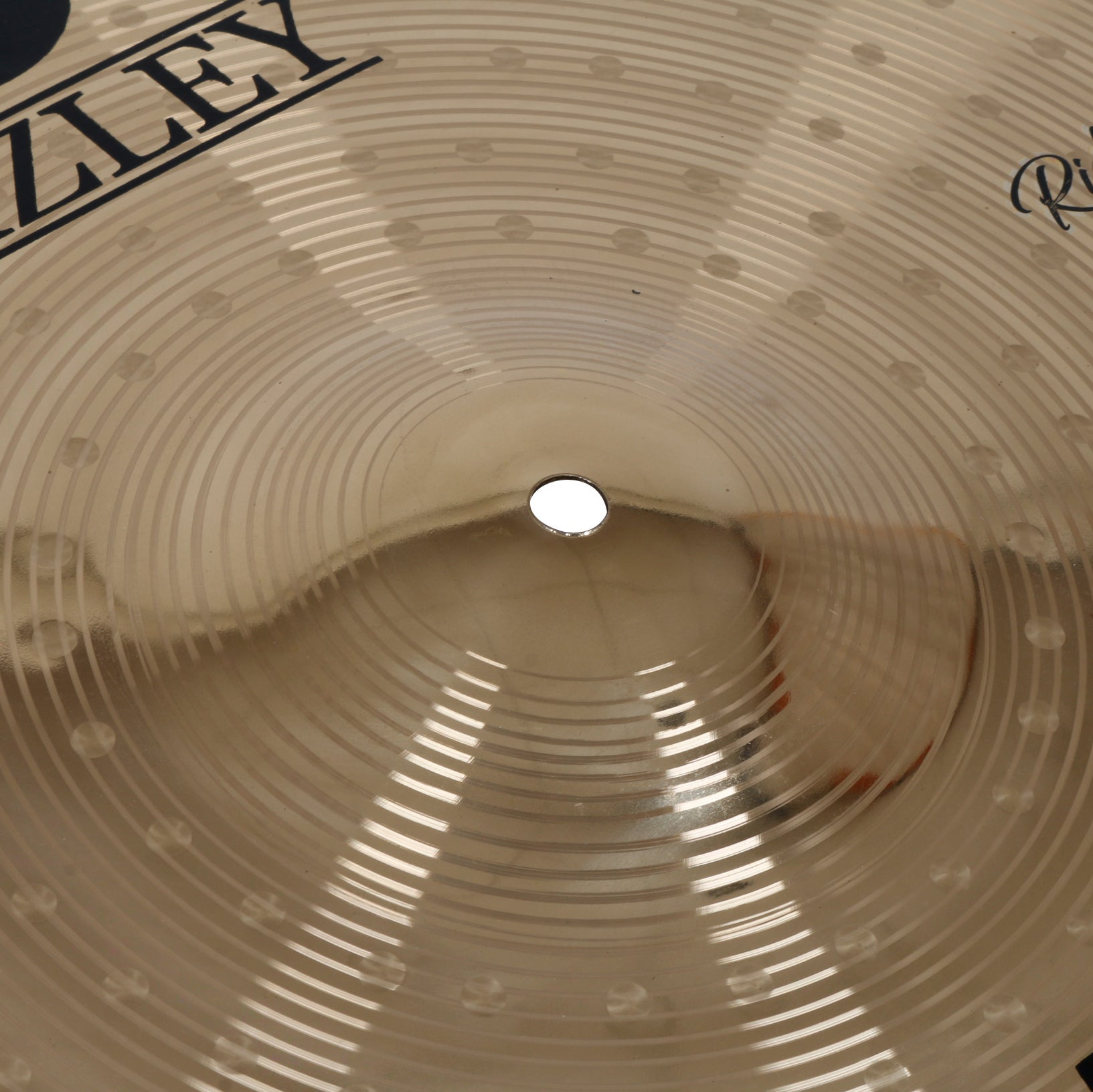 Gold cymbal with concentric grooves, a hole in the center, and lettering.