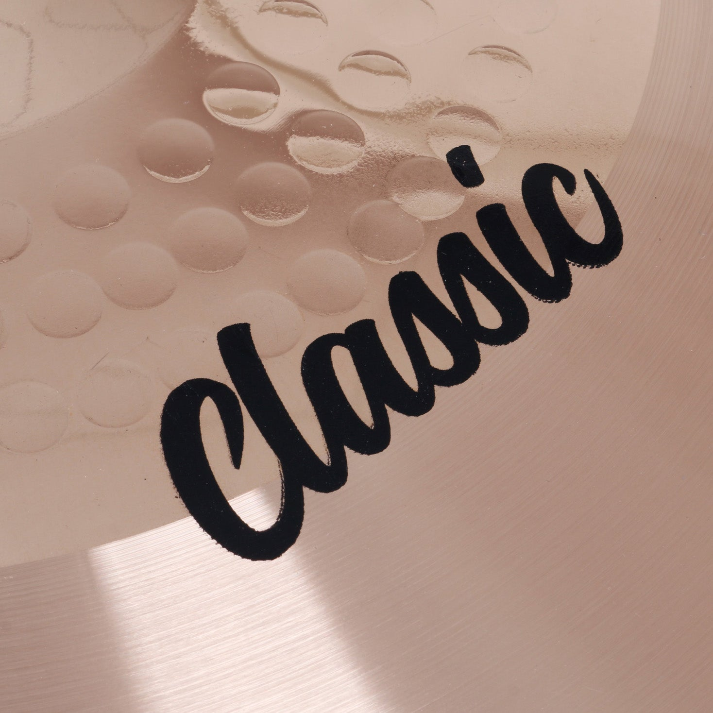 Close-up of a copper cymbal with the word „Classic“ in black lettering.