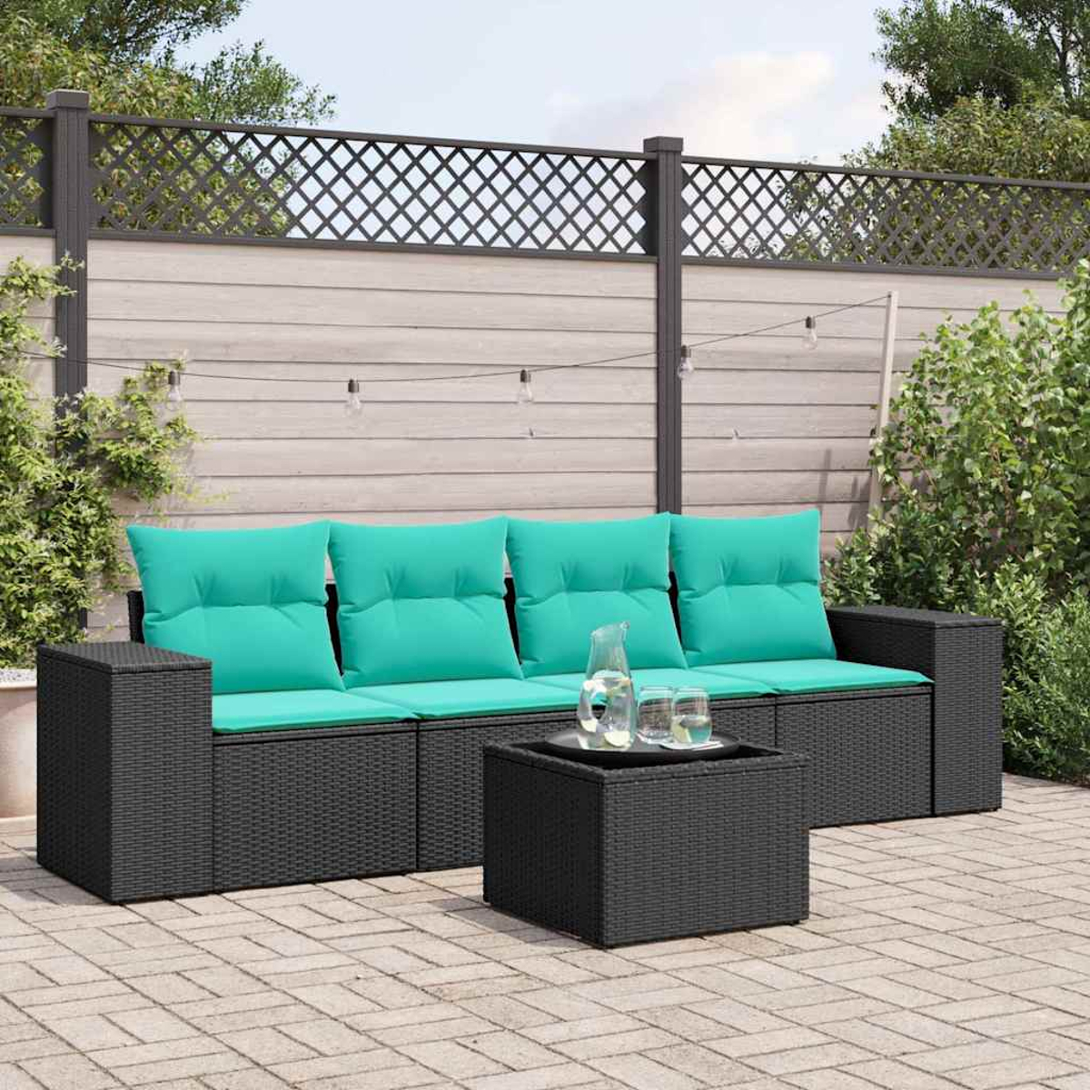 Ein dunkles Rattan-Sofa mit helltürkisen Kissen und einem Couchtisch im Freien.