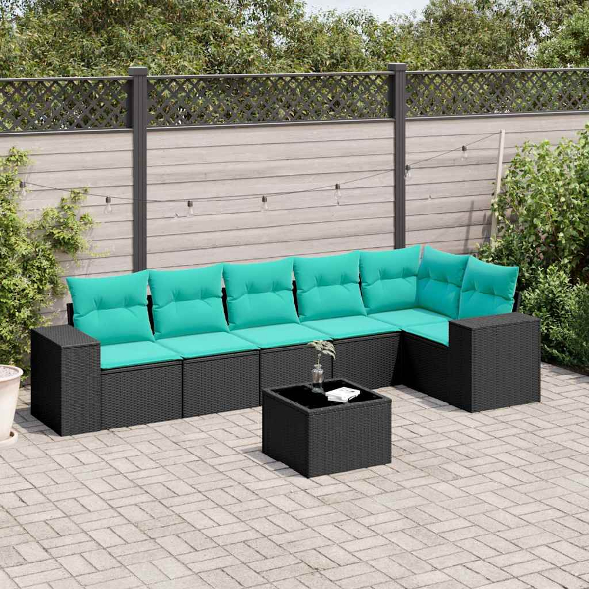 Ein schwarzes modulares Outdoor-Sofa mit türkisfarbenen Kissen steht auf einer gepflasterten Terrasse.