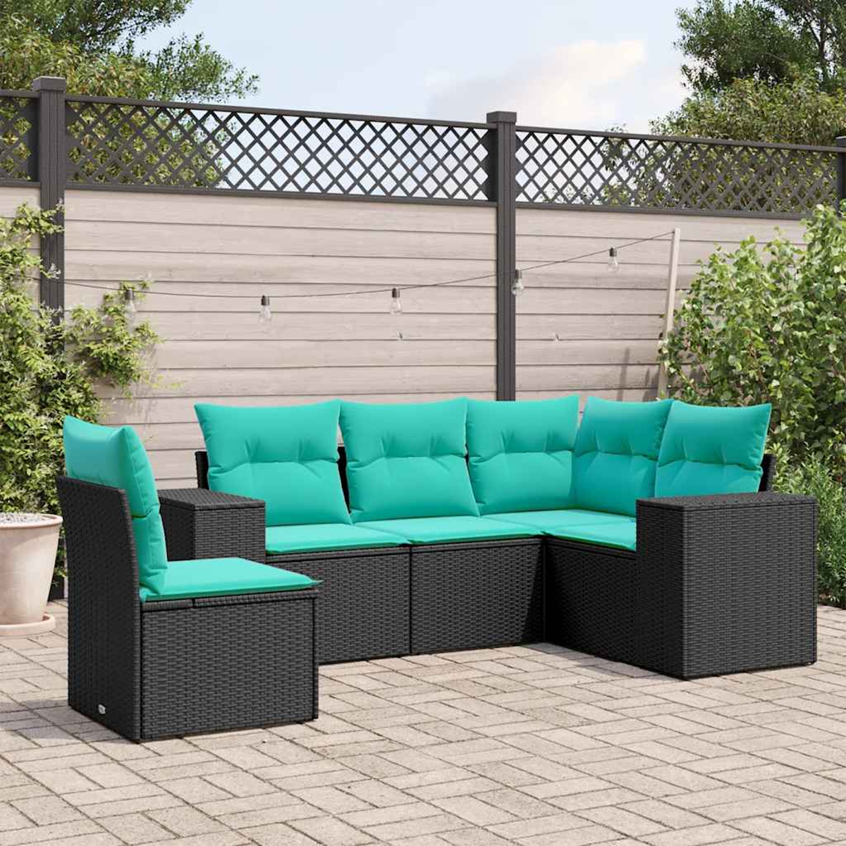 Gartenlounge mit schwarzen Rattansofas und türkisen Kissen auf einer Terrasse.