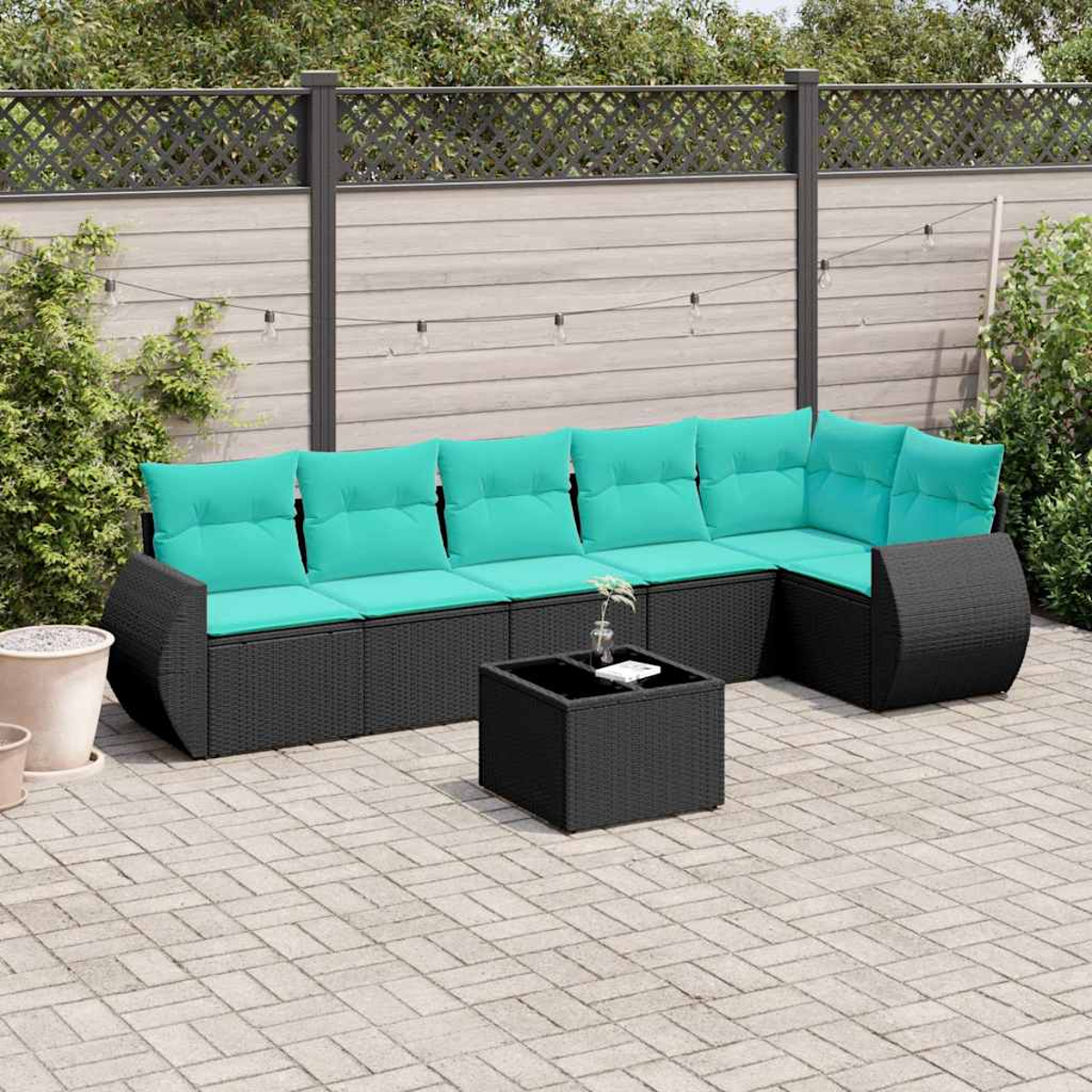 Schwarzes Lounge-Set mit türkisfarbenen Kissen auf einer gepflasterten Terrasse.