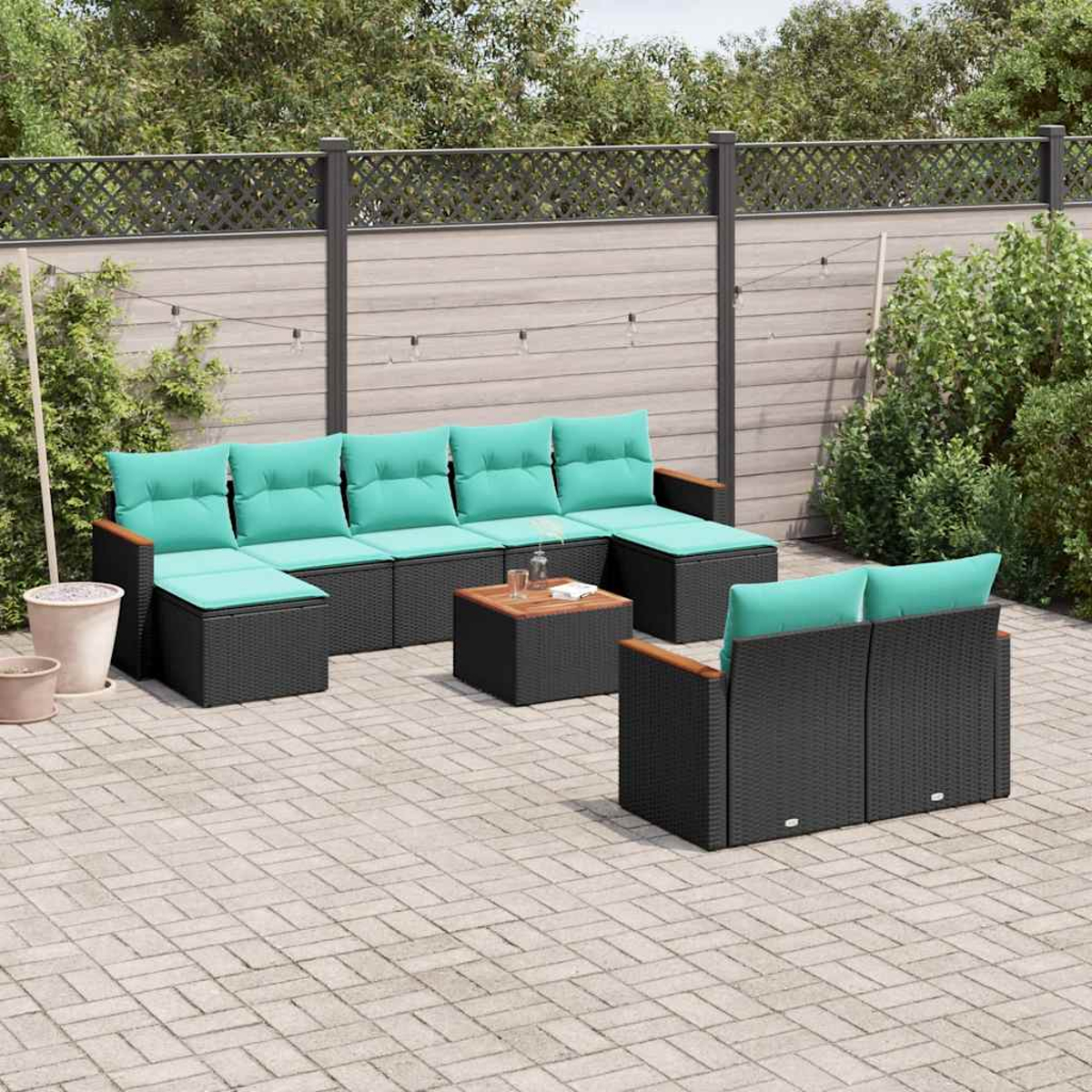 Ein dunkles Gartenmöbel-Set mit türkisfarbenen Kissen und einem Couchtisch auf einer Kopfsteinpflasterterrasse.