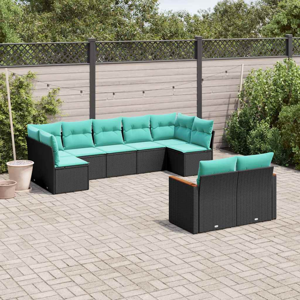 Dunkelgraue Rattan-Lounge-Möbel mit türkisfarbenen Kissen auf einer Kopfsteinpflasterterrasse.