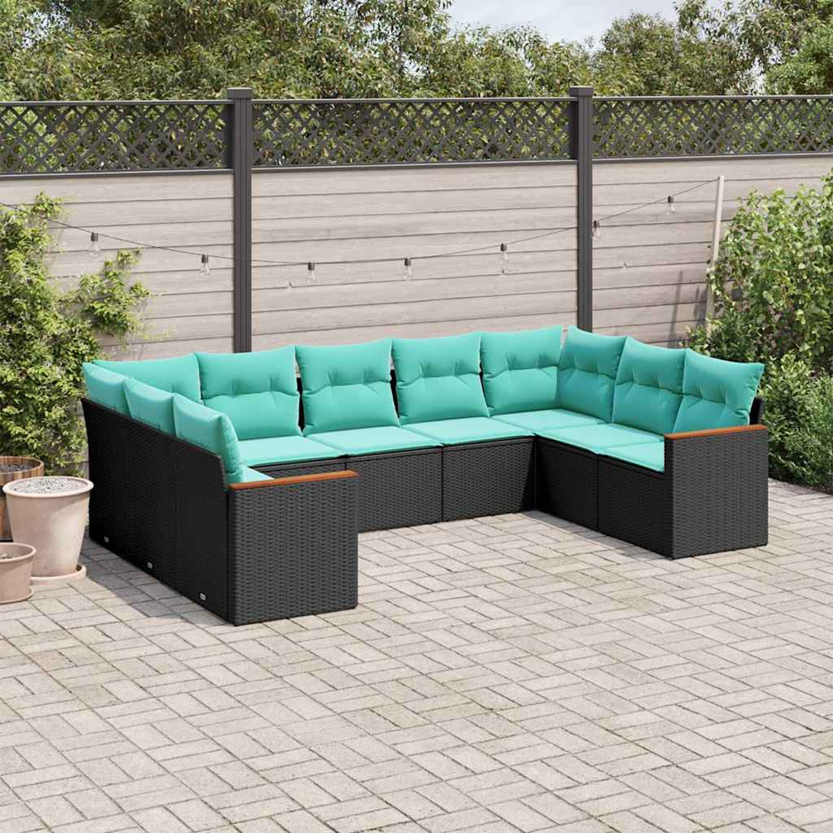 Moderne schwarze Rattan-Lounge-Garnitur mit türkisfarbenen Kissen auf gepflastertem Hof.