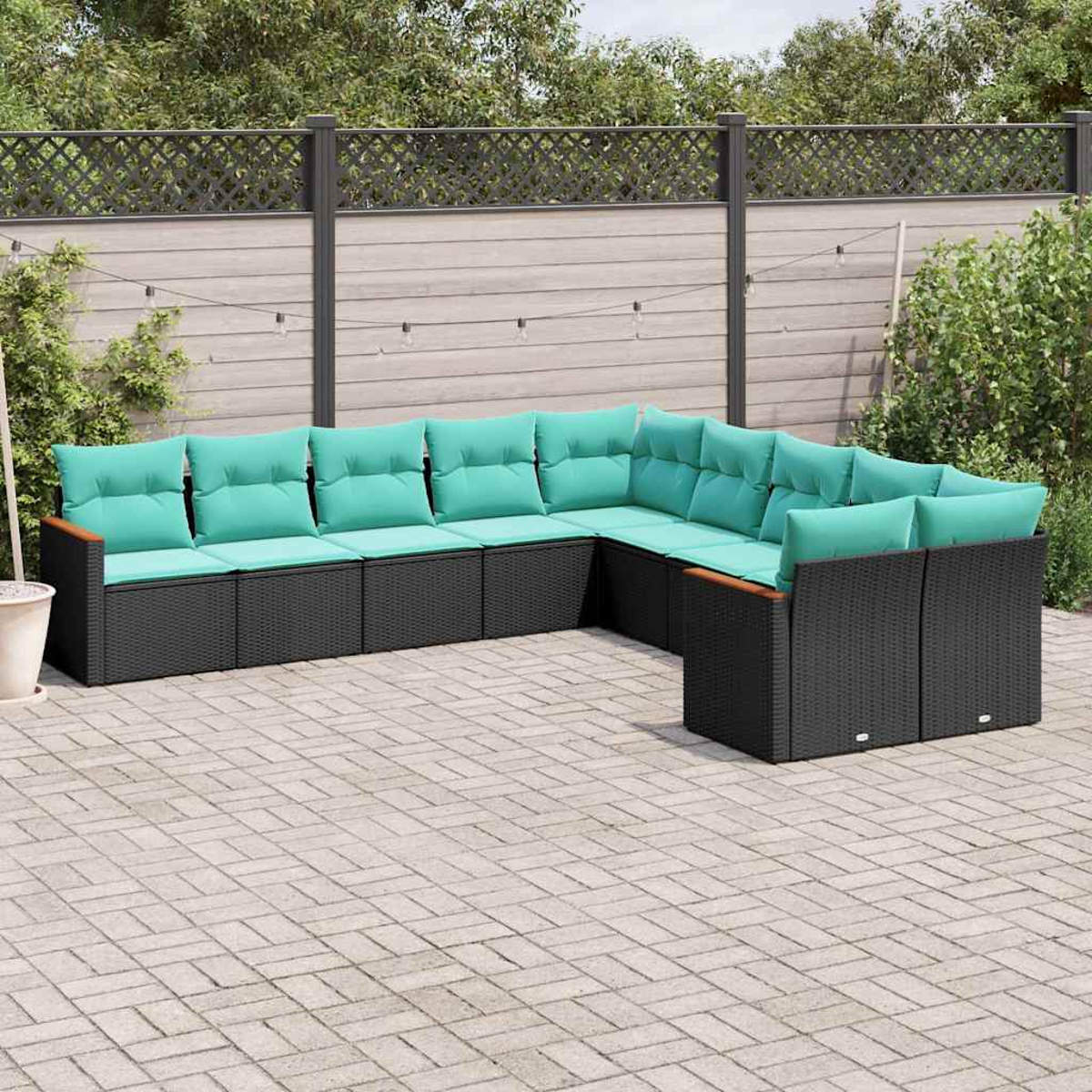 Ein schwarzes Lounge-Ecksofa mit türkisfarbenen Kissen auf einer gepflasterten Terrasse.