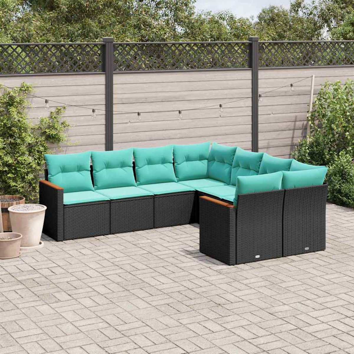Eine schwarze modulare Outdoor-Couch mit türkisfarbenen Kissen steht auf einer gepflasterten Terrasse.