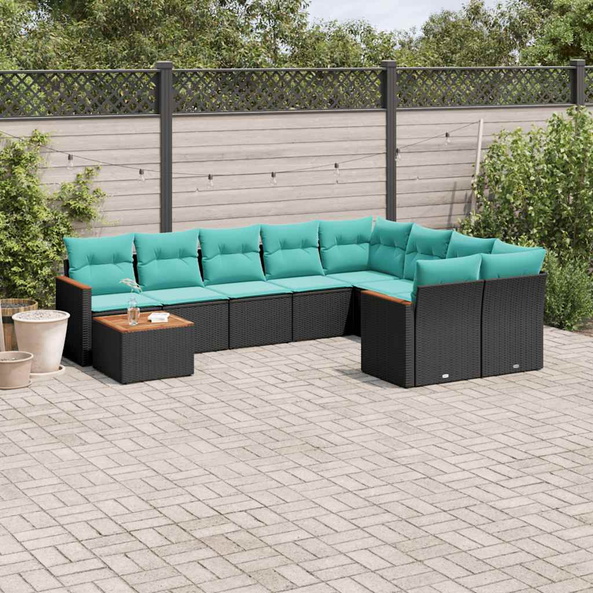 Moderne schwarze Lounge-Garnitur mit türkisen Kissen auf einer gepflasterten Terrasse.