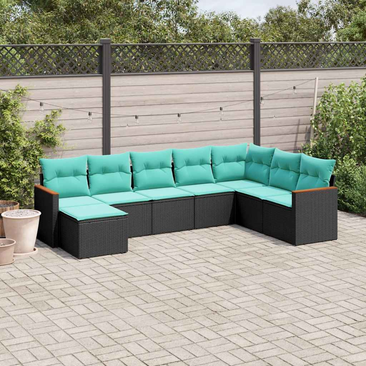 Moderne Rattan-Lounge mit türkisfarbenen Kissen auf gepflasterter Terrasse.